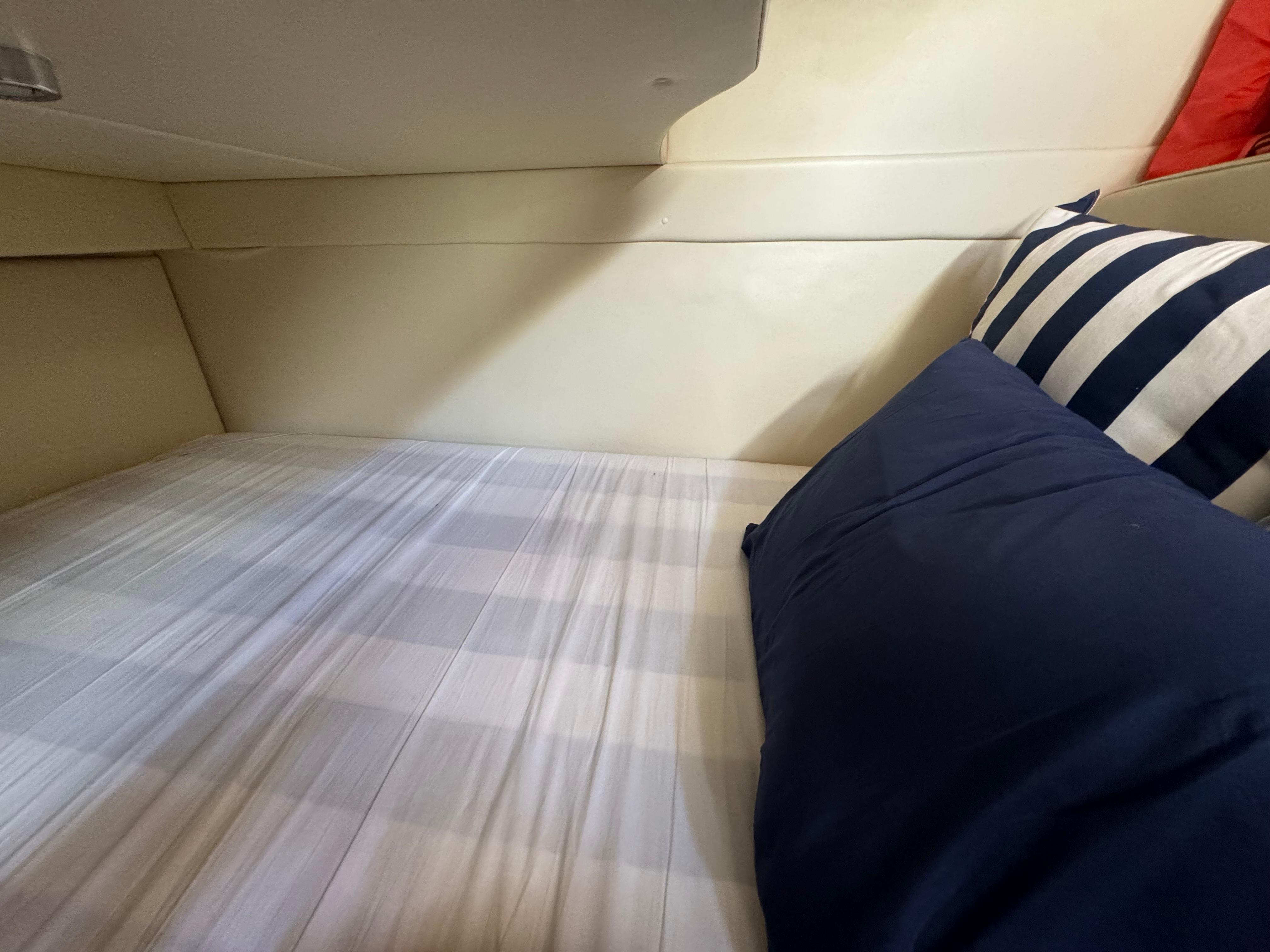 Cozy cabin bed in 2008 Bayliner 300 Ciera with striped pillow and blue bedding.