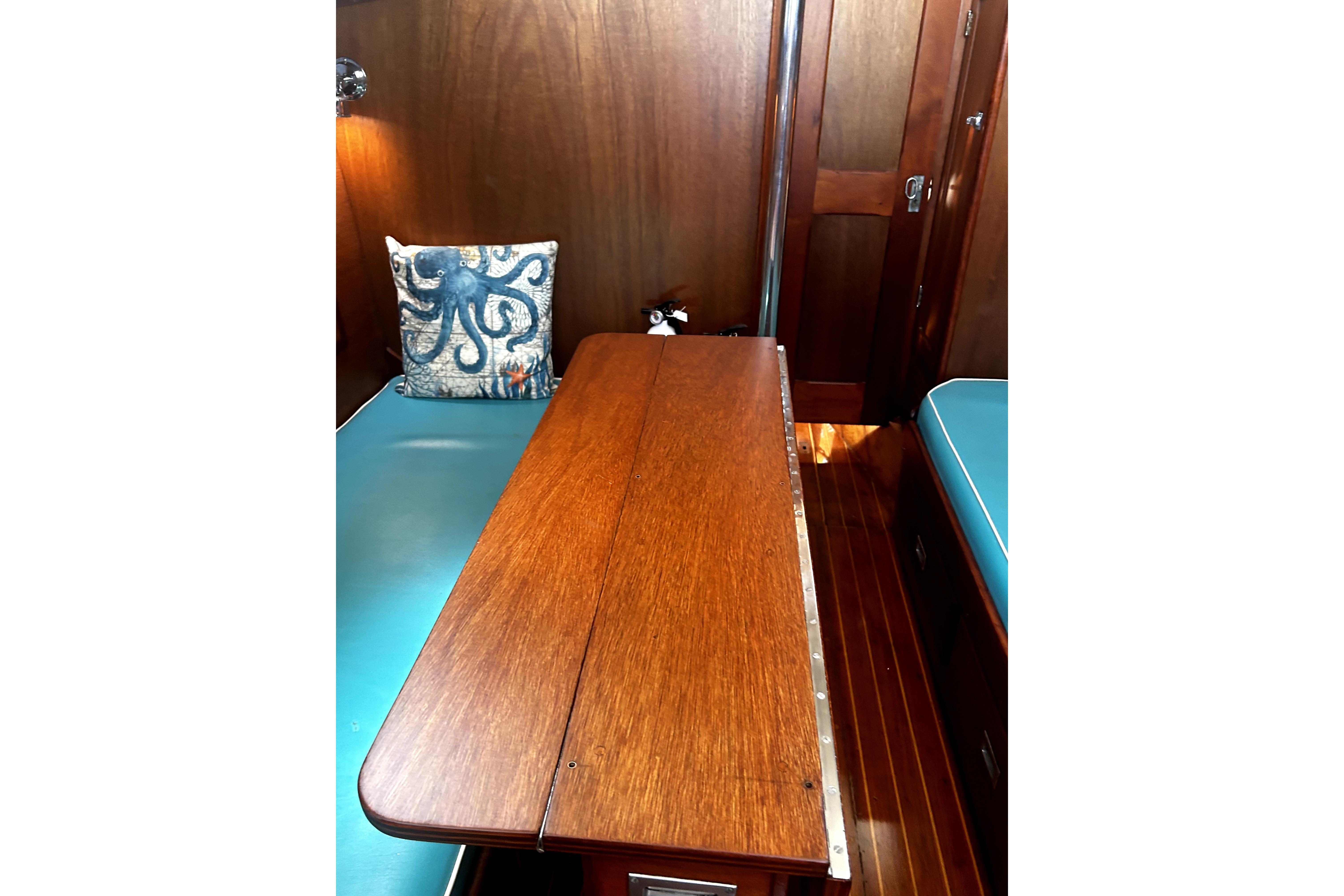 Hinckley Pilot 35 (1964) cabin interior with wooden table and octopus-themed cushion.