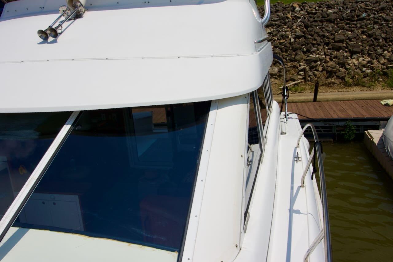 1996 Silverton 37 Convertible boat docked near rocky shoreline.