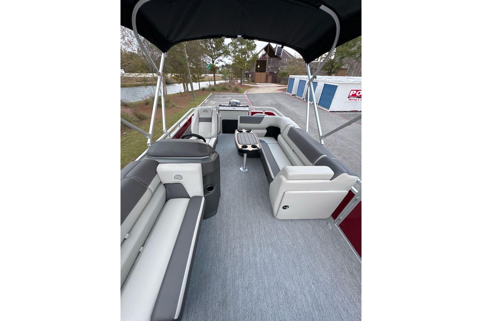 2026 Sun Tracker Fishin' Barge 22 DLX interior with seating and table, docked outdoors.