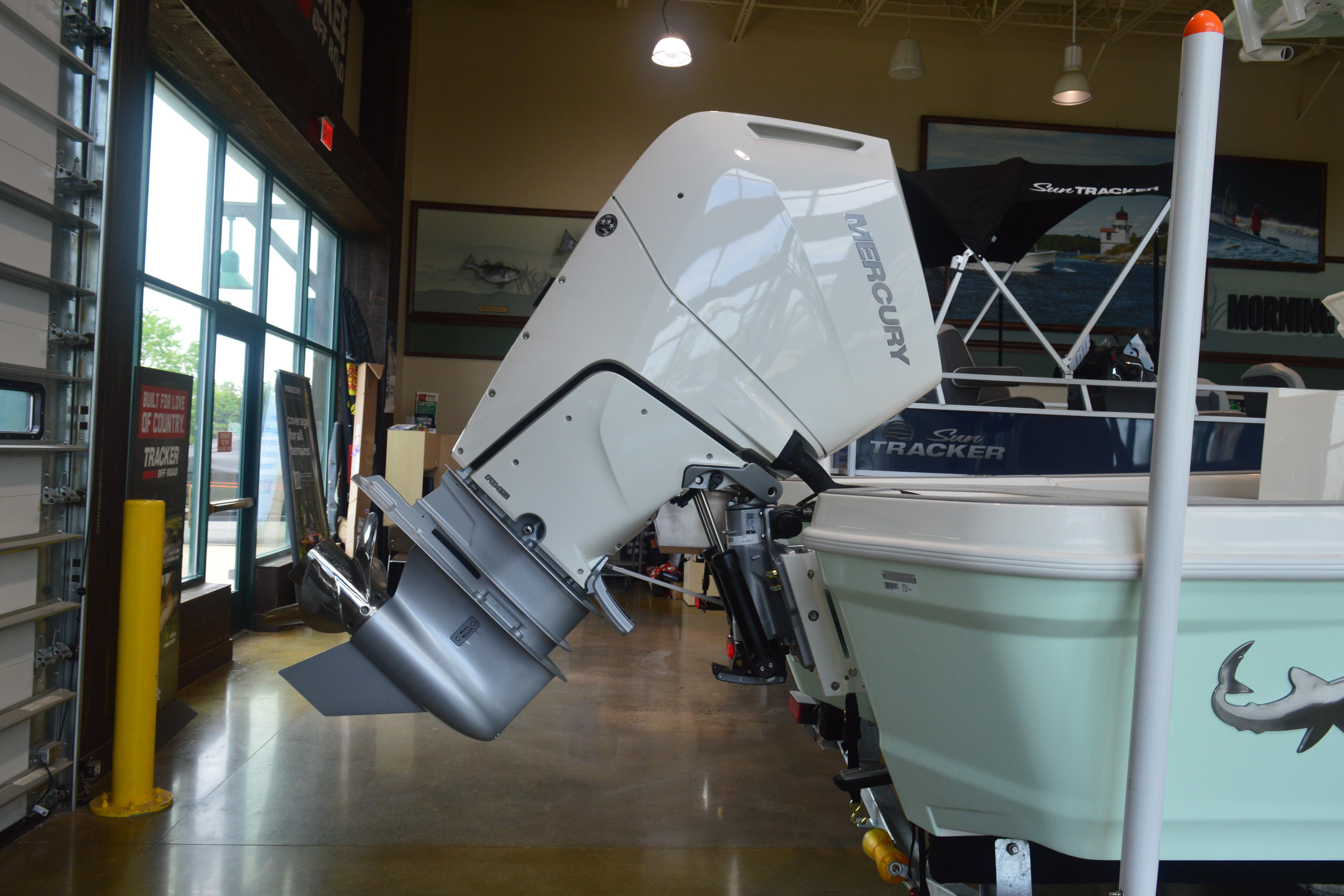 2026 Mako 24 APEX boat with Mercury outboard motor in showroom.