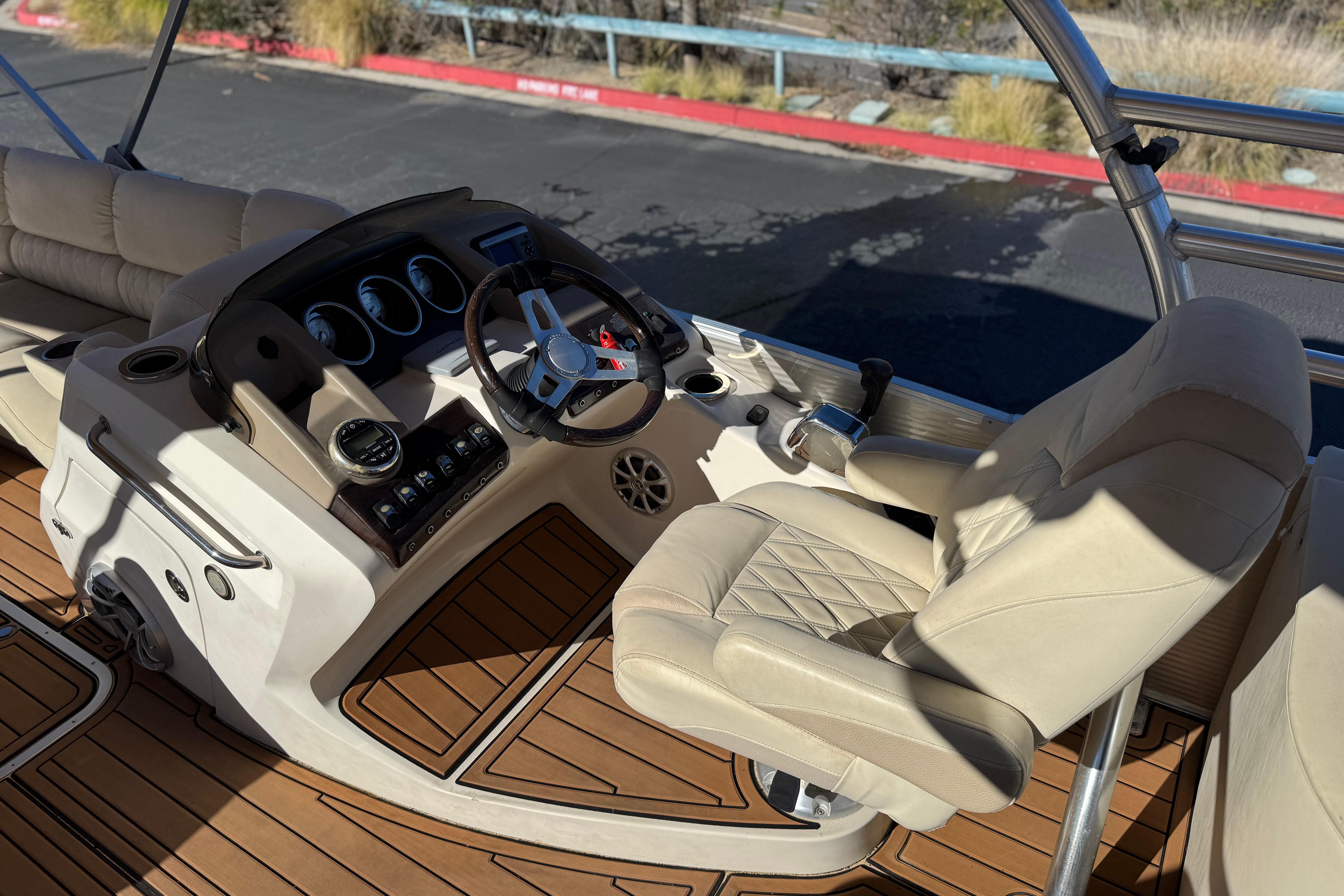 2013 Bennington 2575QCW I/O boat interior with steering wheel and beige seating.