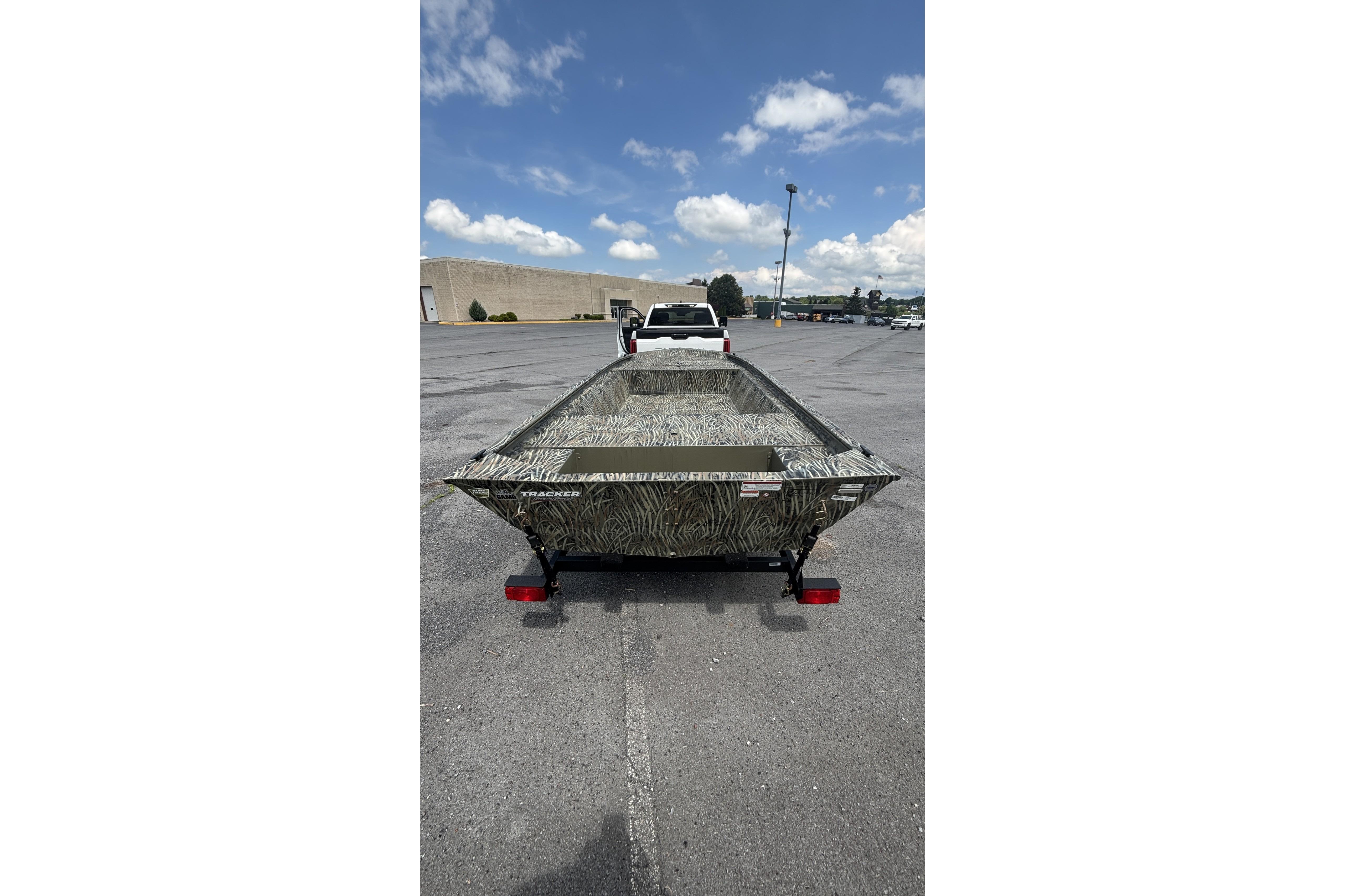 2026 Tracker Grizzly 1648 Utility boat on trailer in parking lot, under blue sky.