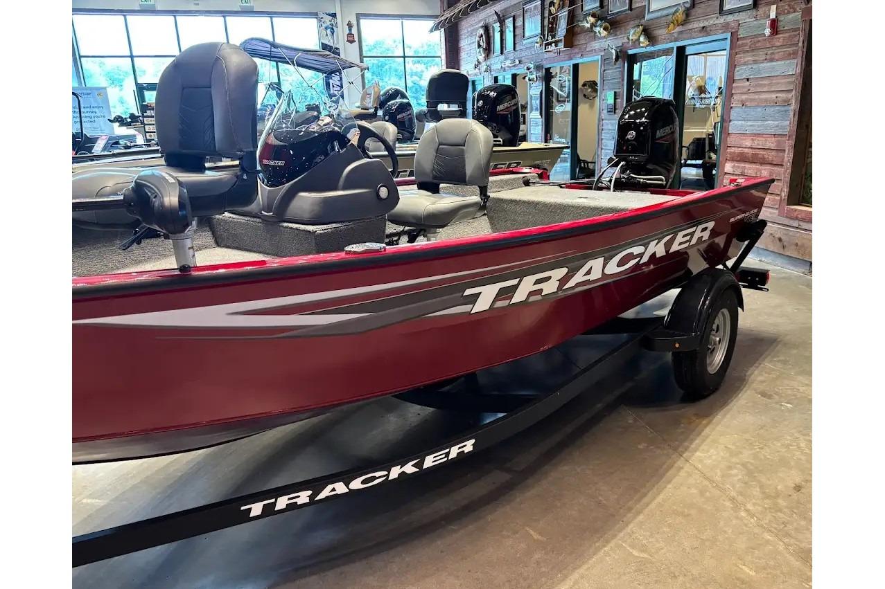 2026 Tracker Super Guide V-16 SC boat in showroom, featuring sleek red design and comfortable seating.
