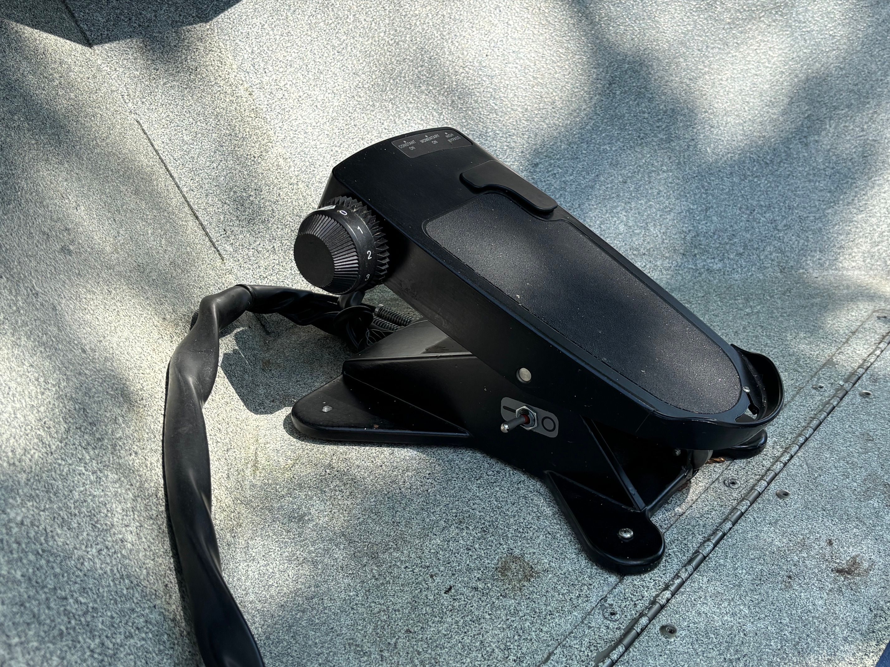 Close-up of a black boat control device on a gray surface.