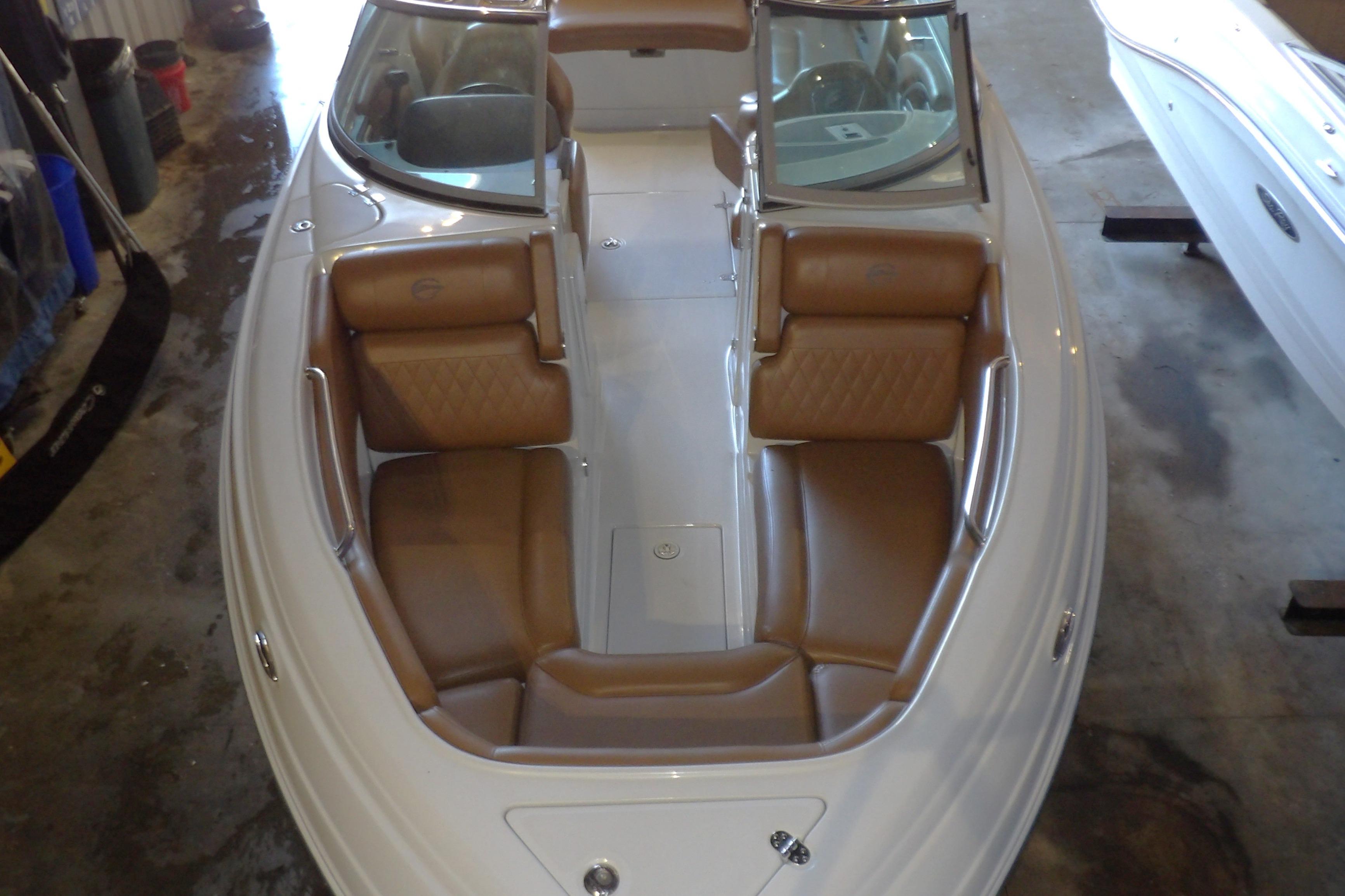 2023 Crownline 250 XSS boat with brown leather seating in a garage setting.