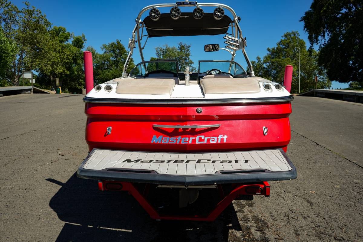 Red 2007 MasterCraft X-45 boat on a ramp, surrounded by trees.