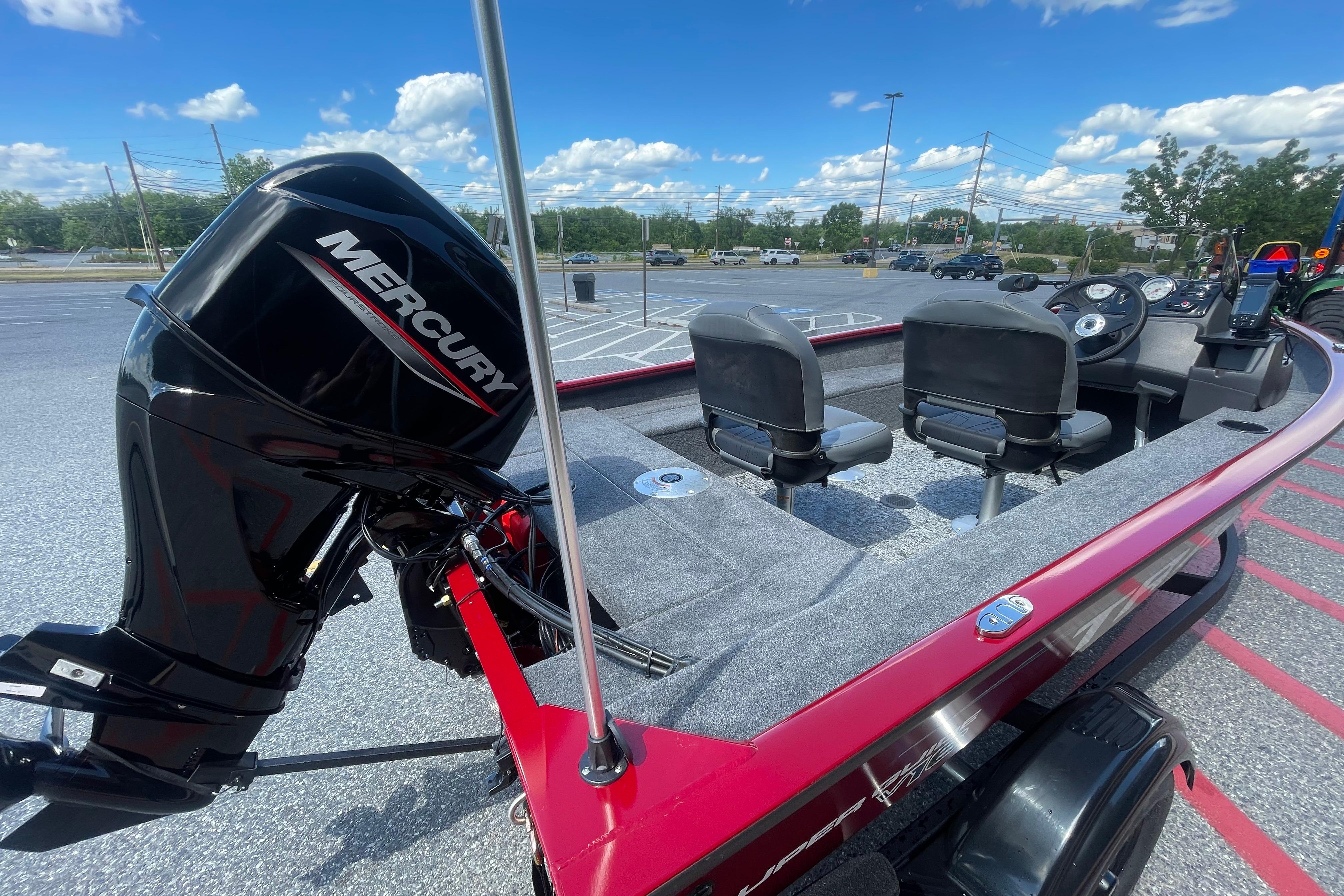 2026 Tracker Super Guide V-16 SC boat with Mercury engine in parking lot.