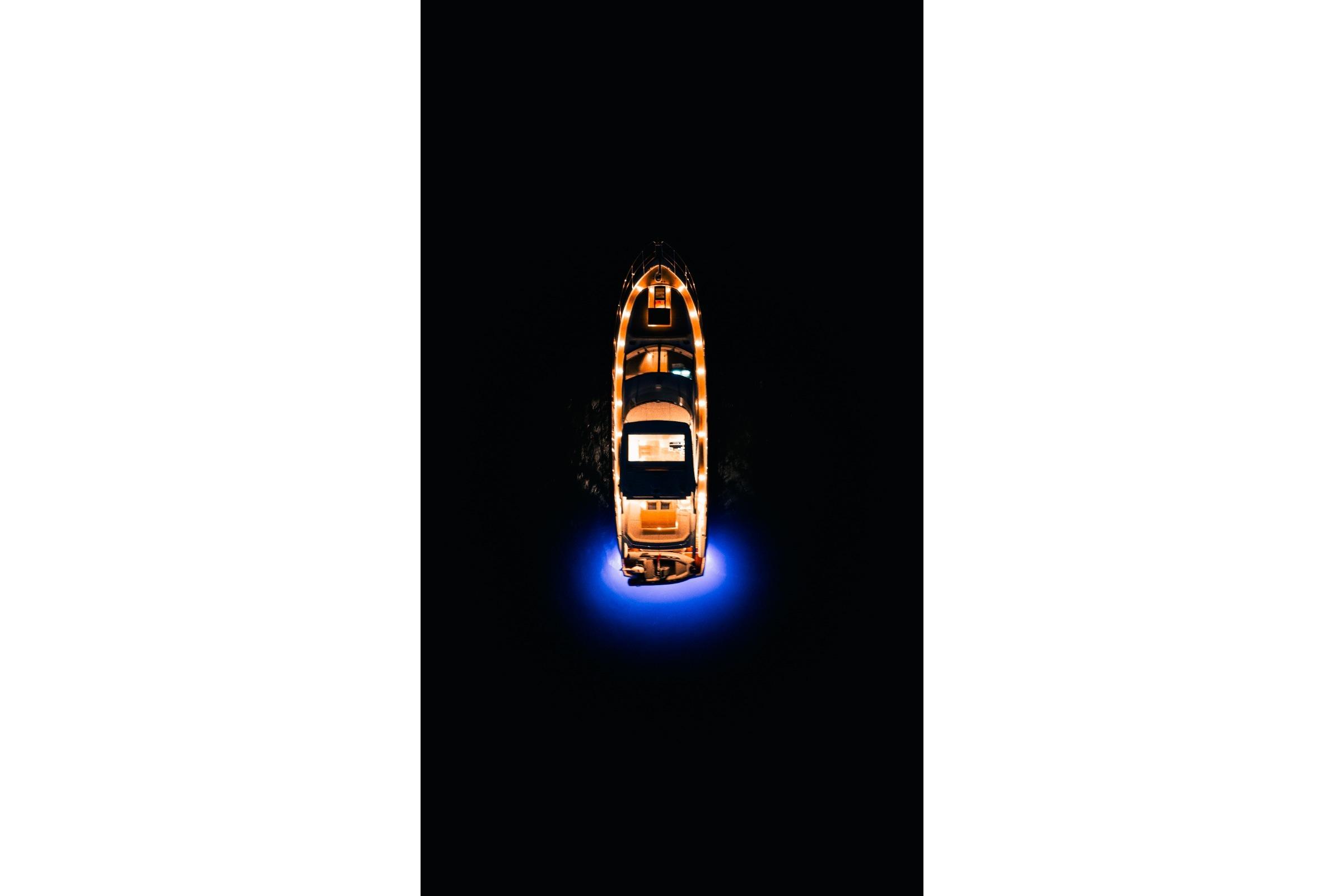 Top view of 2024 Sunseeker Manhattan 55 yacht with glowing blue lights at night.