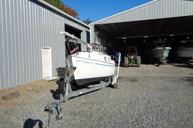 2007 Sanibel 18 Pocket Cruiser sailboat on trailer outside metal storage building.
