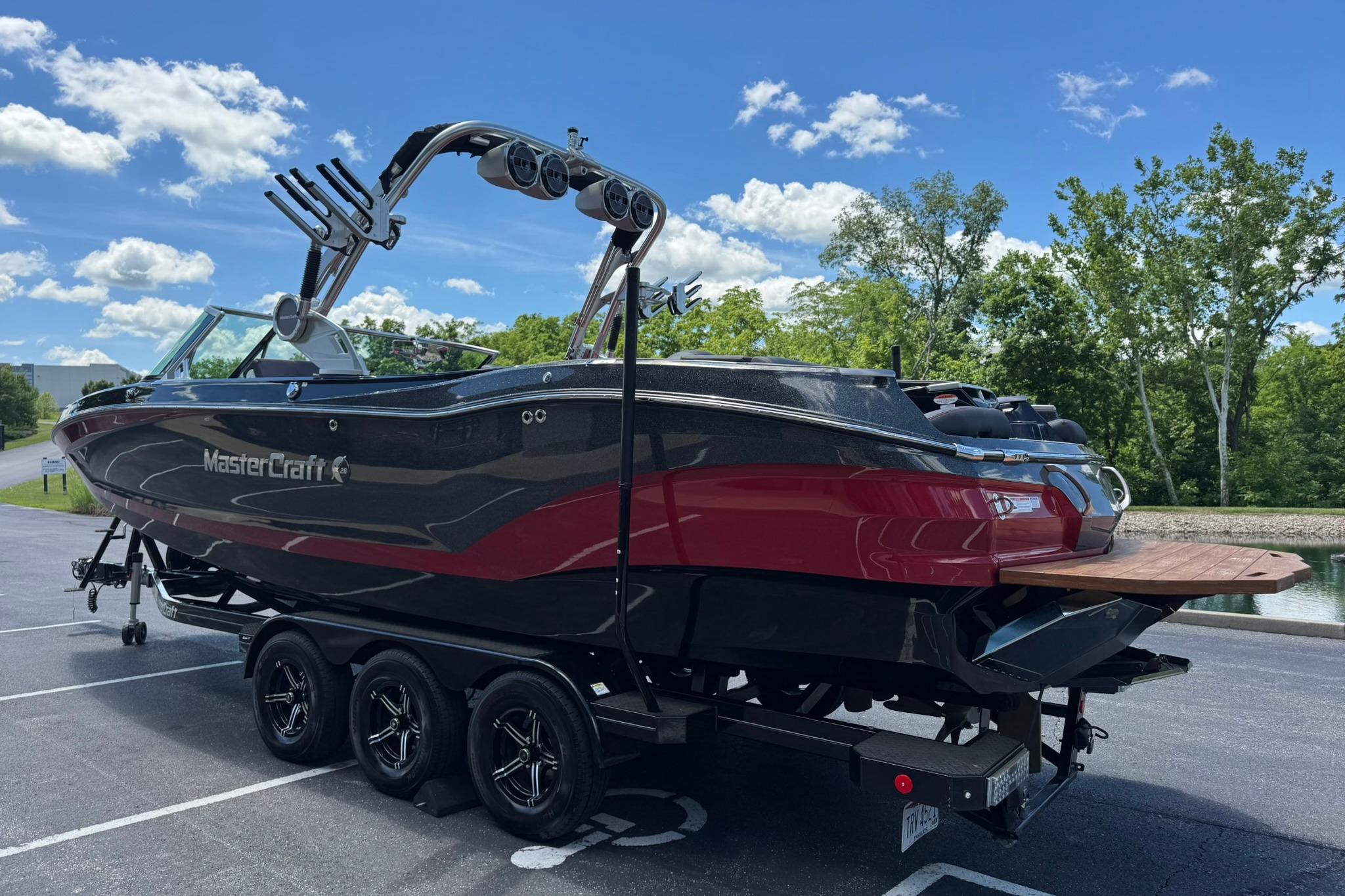 2021 MasterCraft X26 boat on trailer, parked outdoors under a clear blue sky.