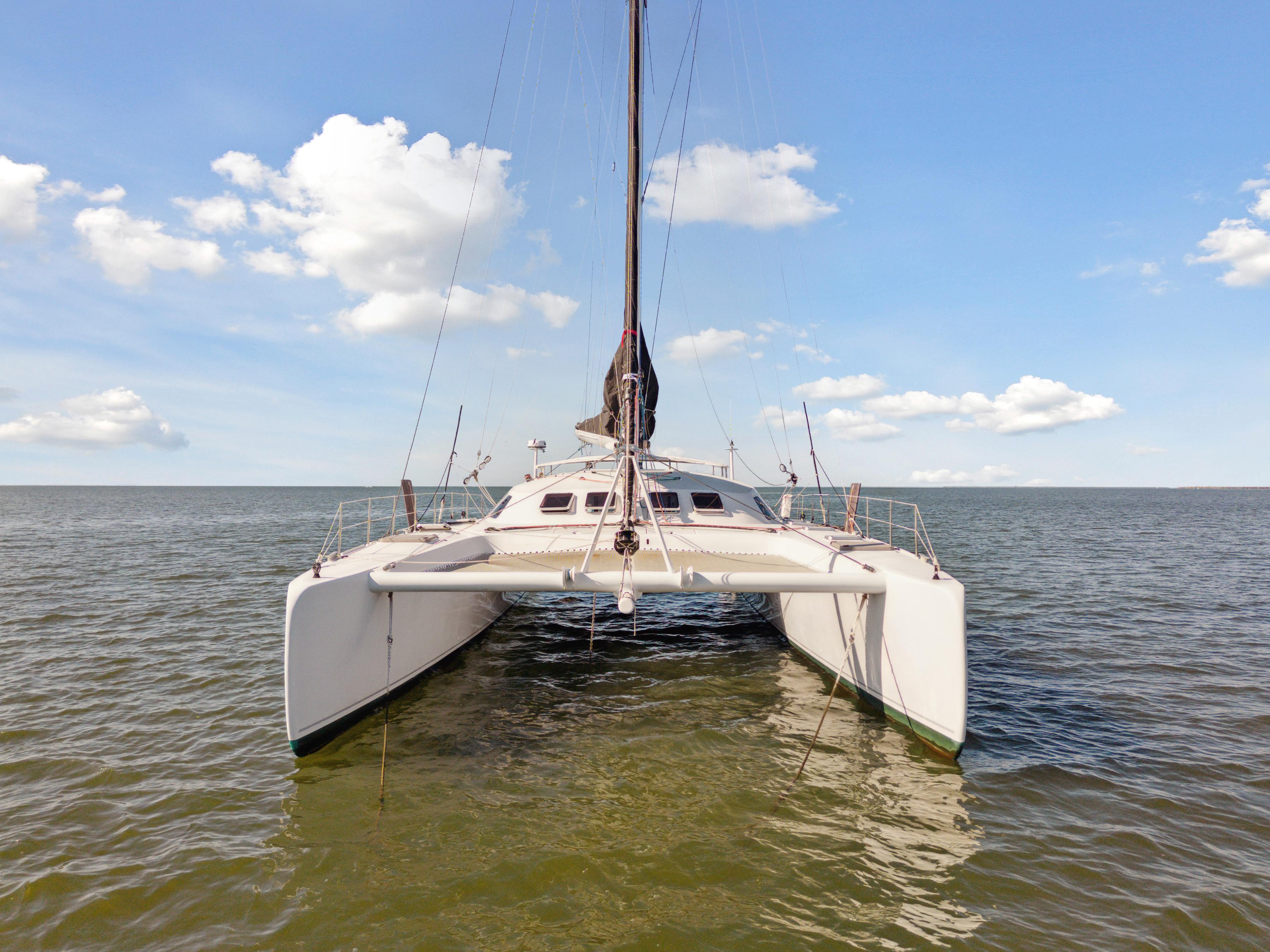 Catamaran Technologie Marine Entincelle 60, 1999 model, sailing on calm sea under blue sky.