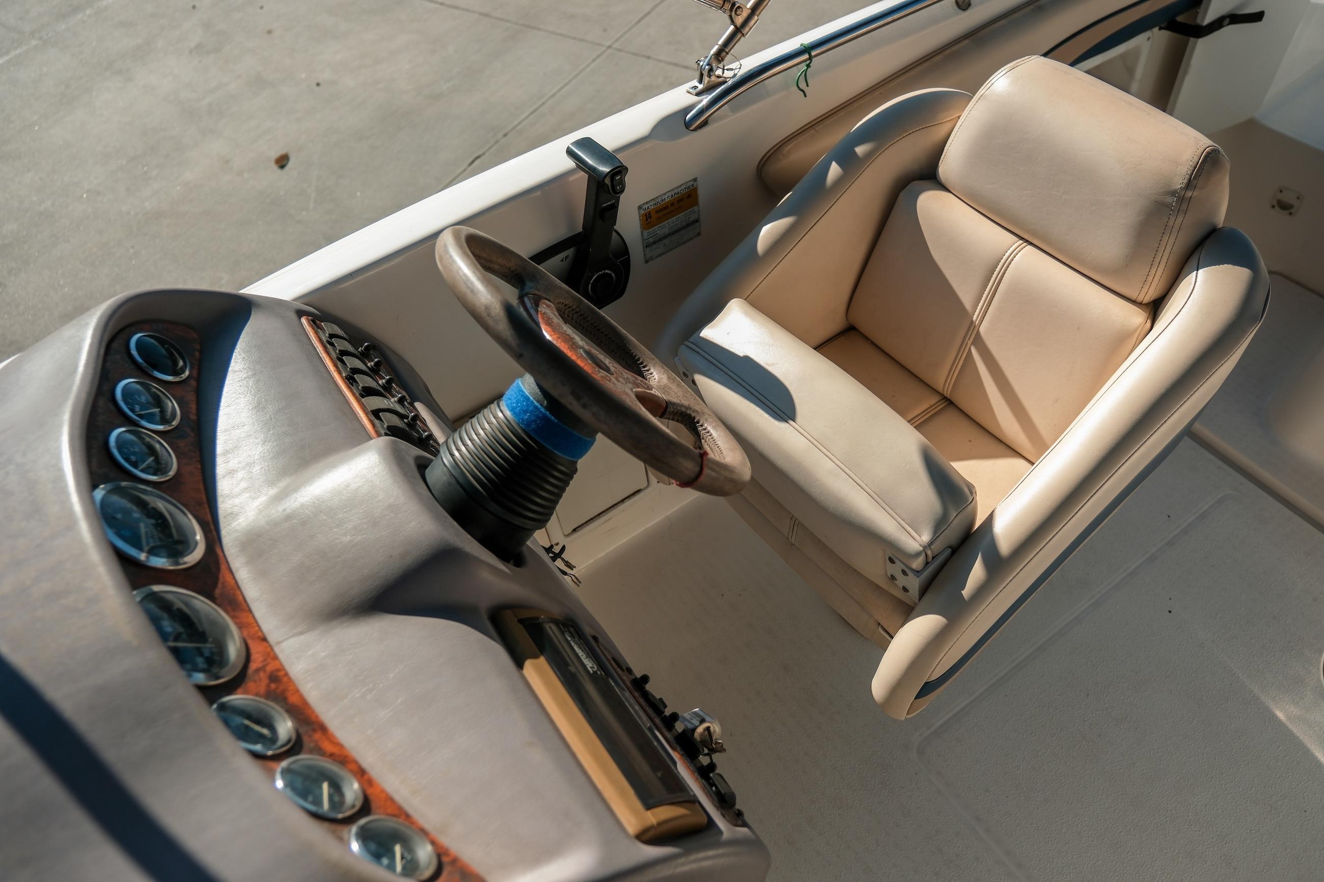 1998 Chaparral 232 Sunesta boat cockpit with steering wheel and beige captain's chair.