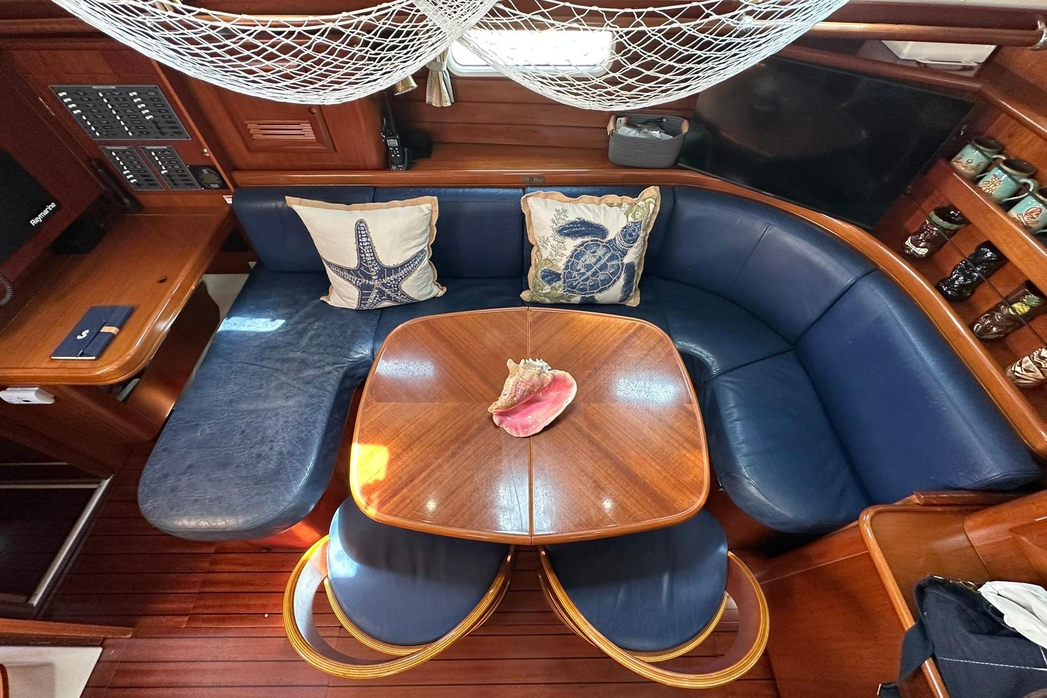 Interior of 2000 Beneteau 50 yacht with blue seating and wooden table.