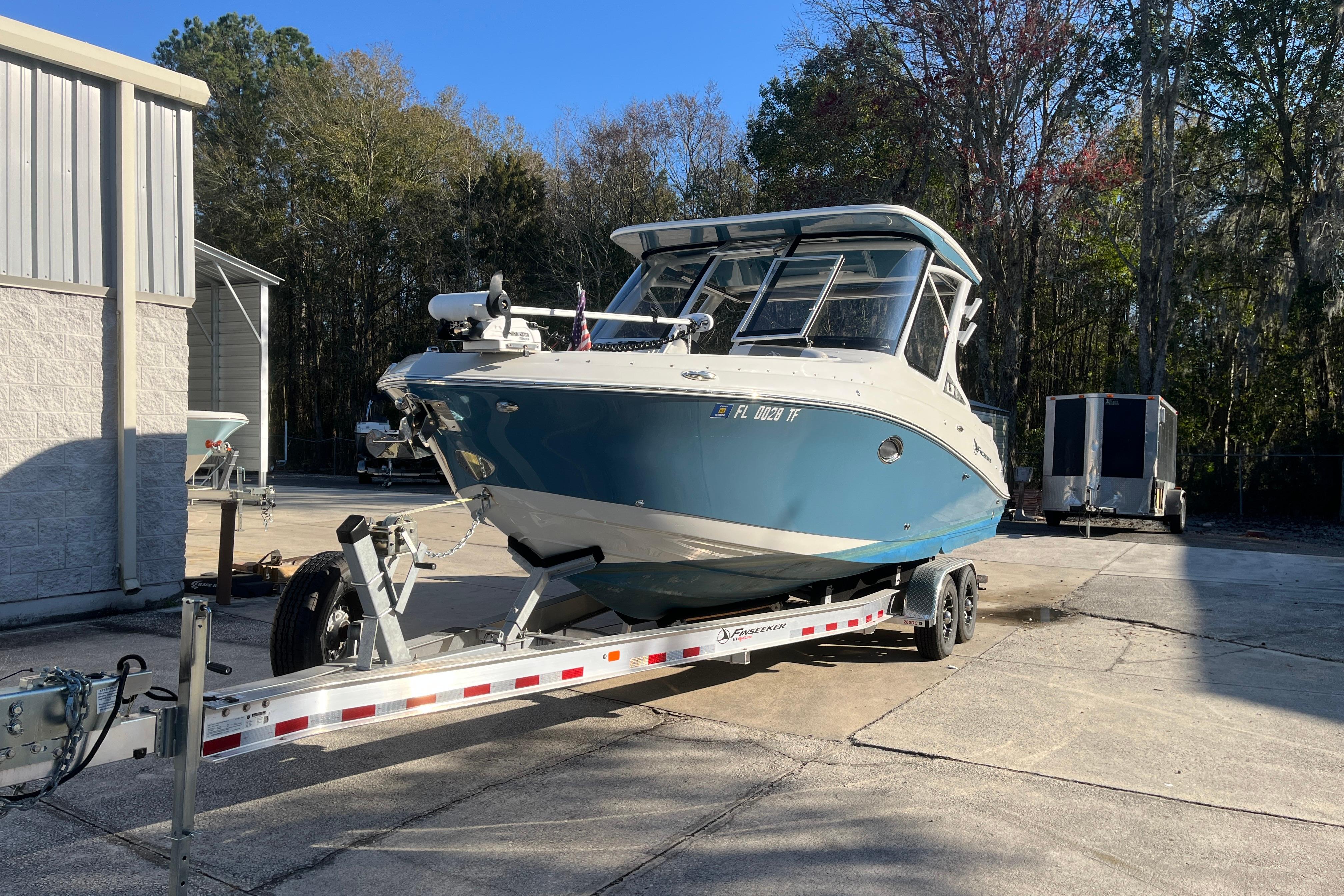 2022 Finseeker 280 DC boat on trailer, parked outdoors near a building.