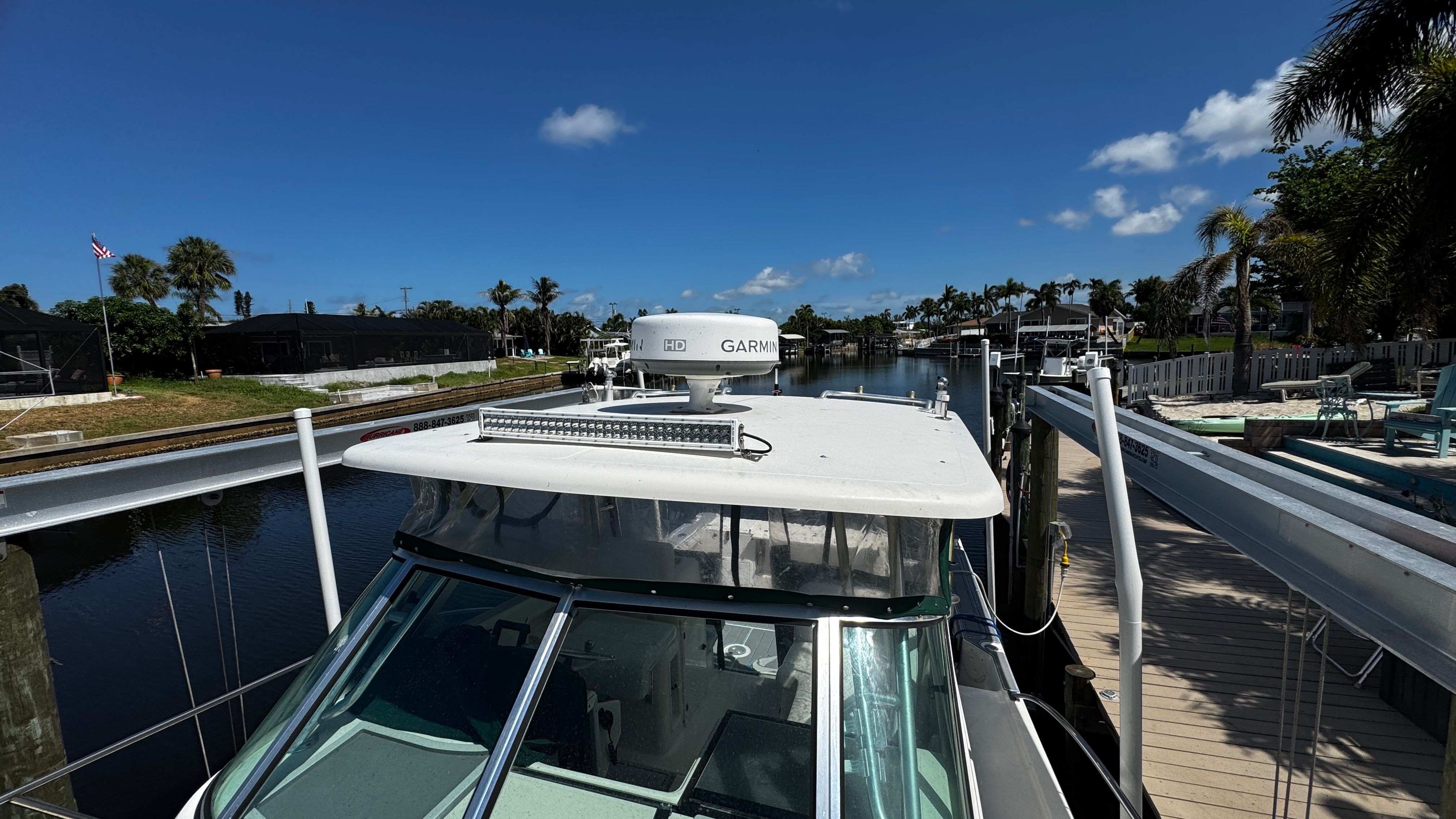 2003 Pursuit 3070 on a calm canal, surrounded by palm trees and houses.