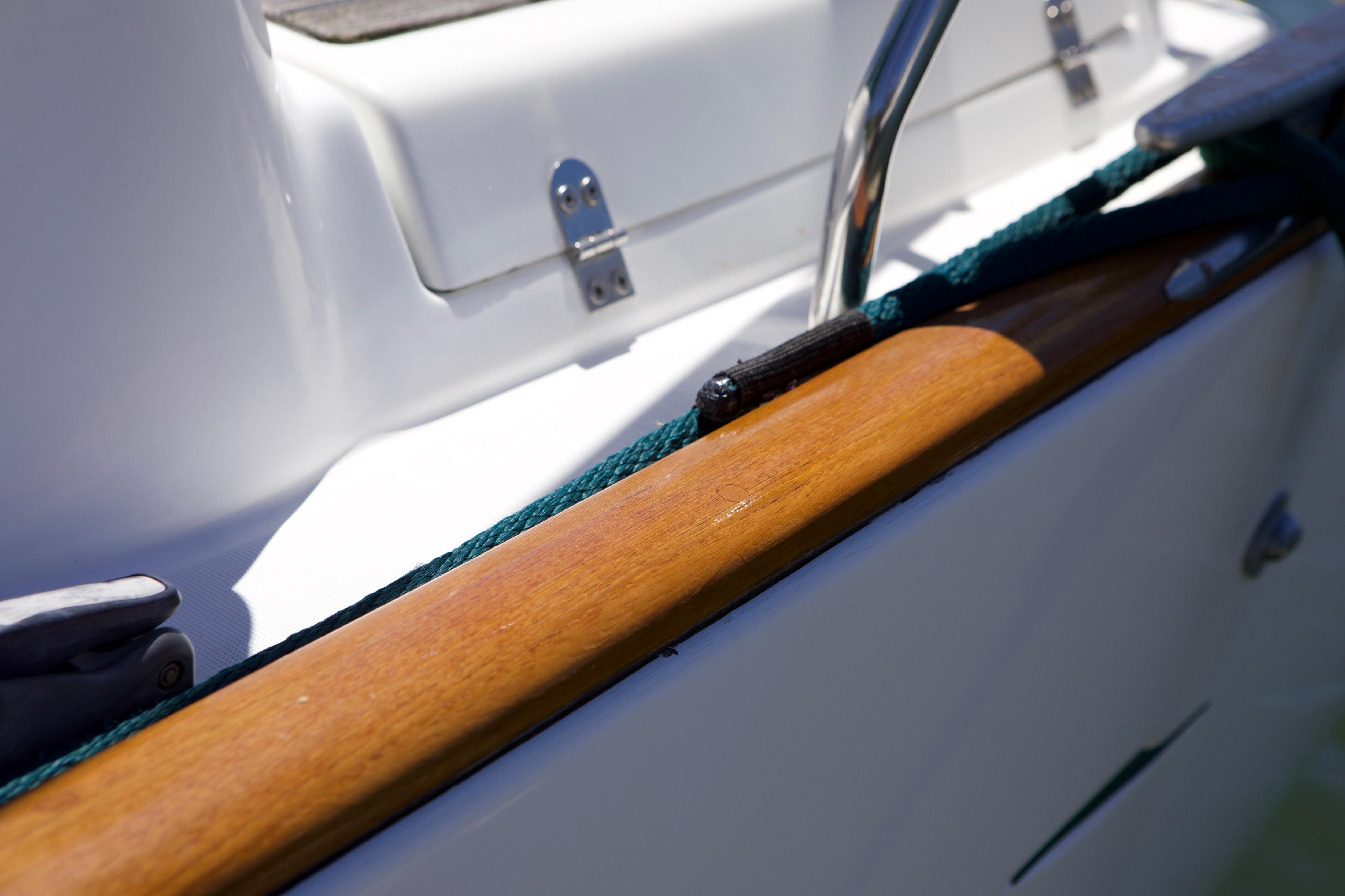 Close-up of 2005 Beneteau 423 yacht's deck with wooden trim and metal fittings.