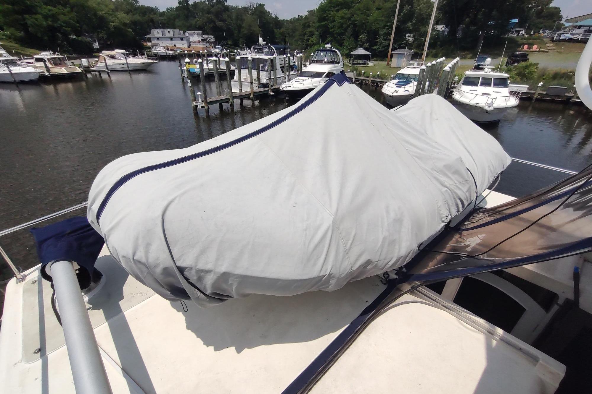 1989 Hyatt Double Cabin Motoryacht docked, covered with a protective tarp, surrounded by other boats.