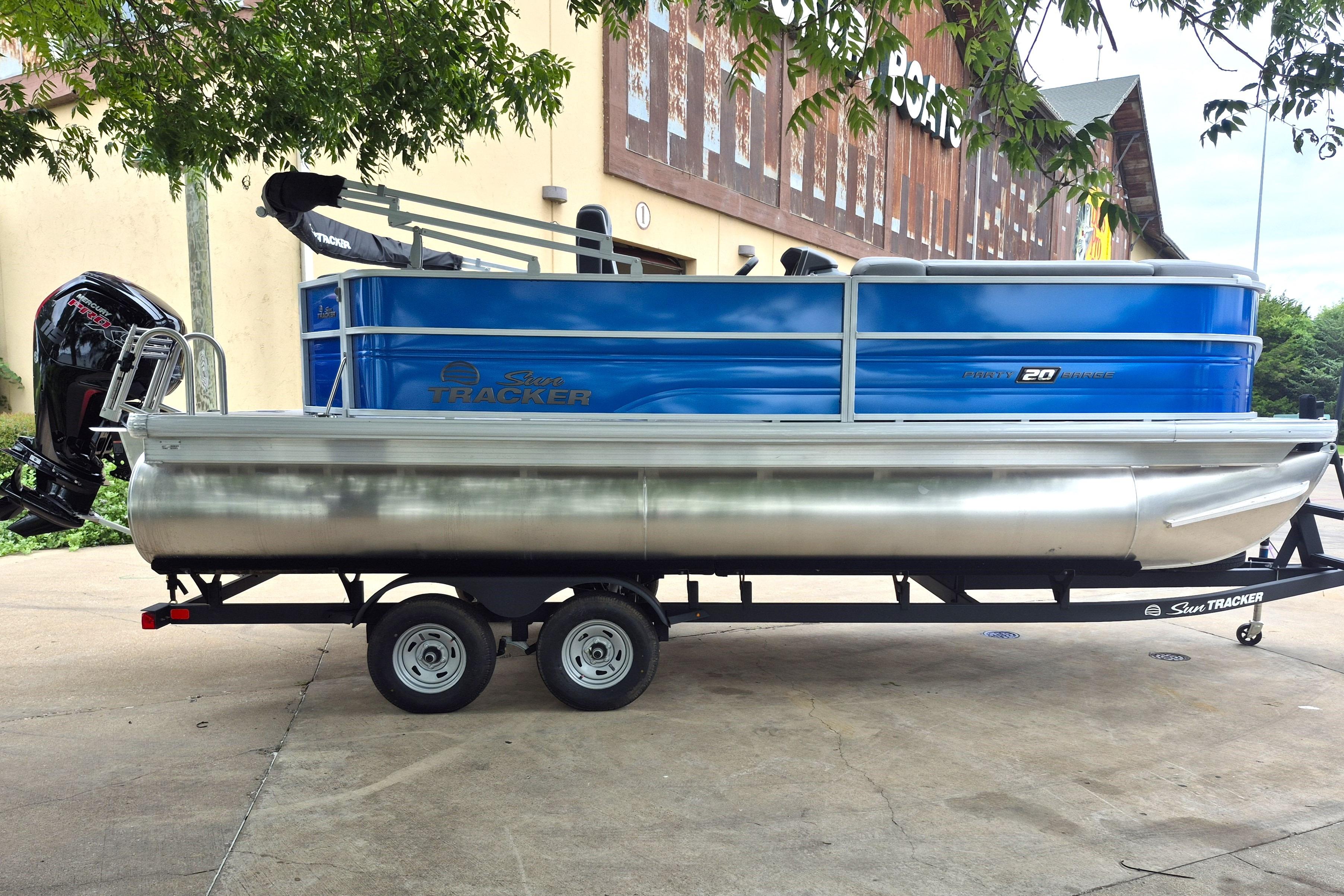 2026 Sun Tracker Party Barge 20 DLX pontoon boat on trailer, parked outdoors.