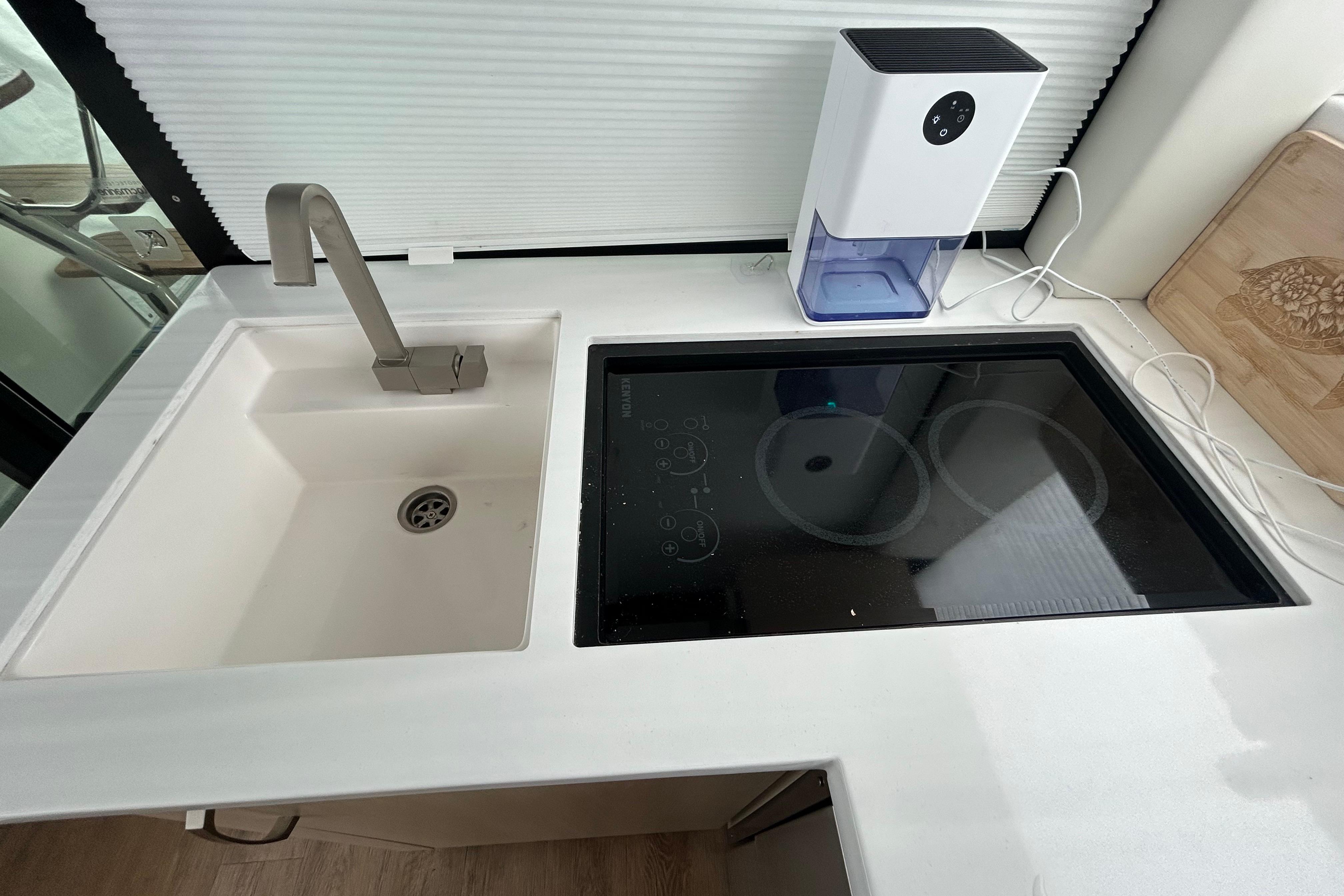 Modern kitchen area in 2023 Regal 38 FXO yacht with sink and induction cooktop.