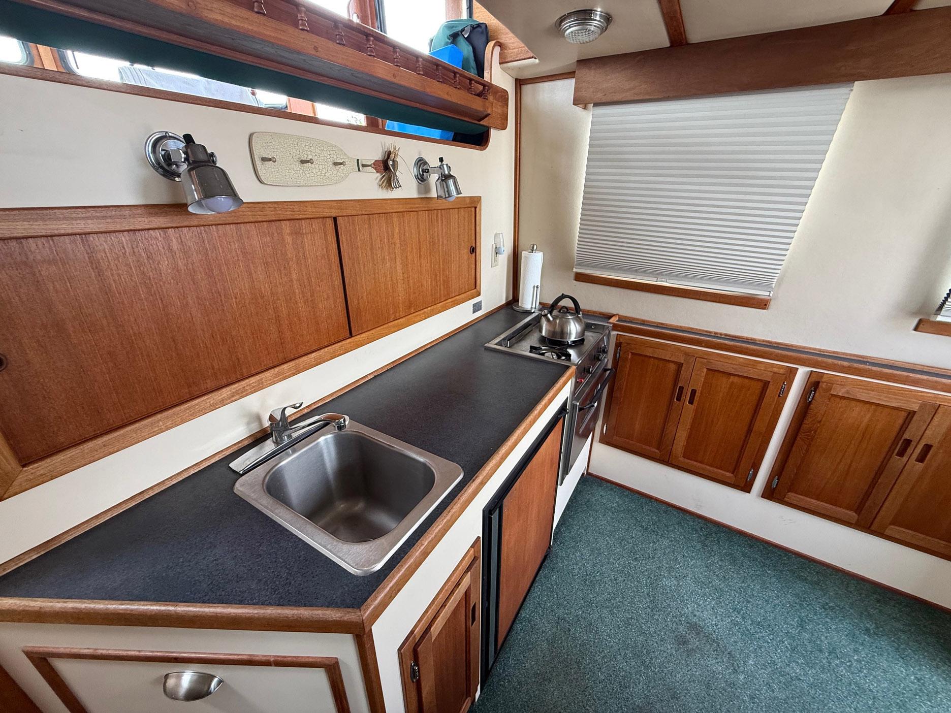 1998 Nordic Tug Trawler kitchen with wooden cabinets, sink, and stove.
