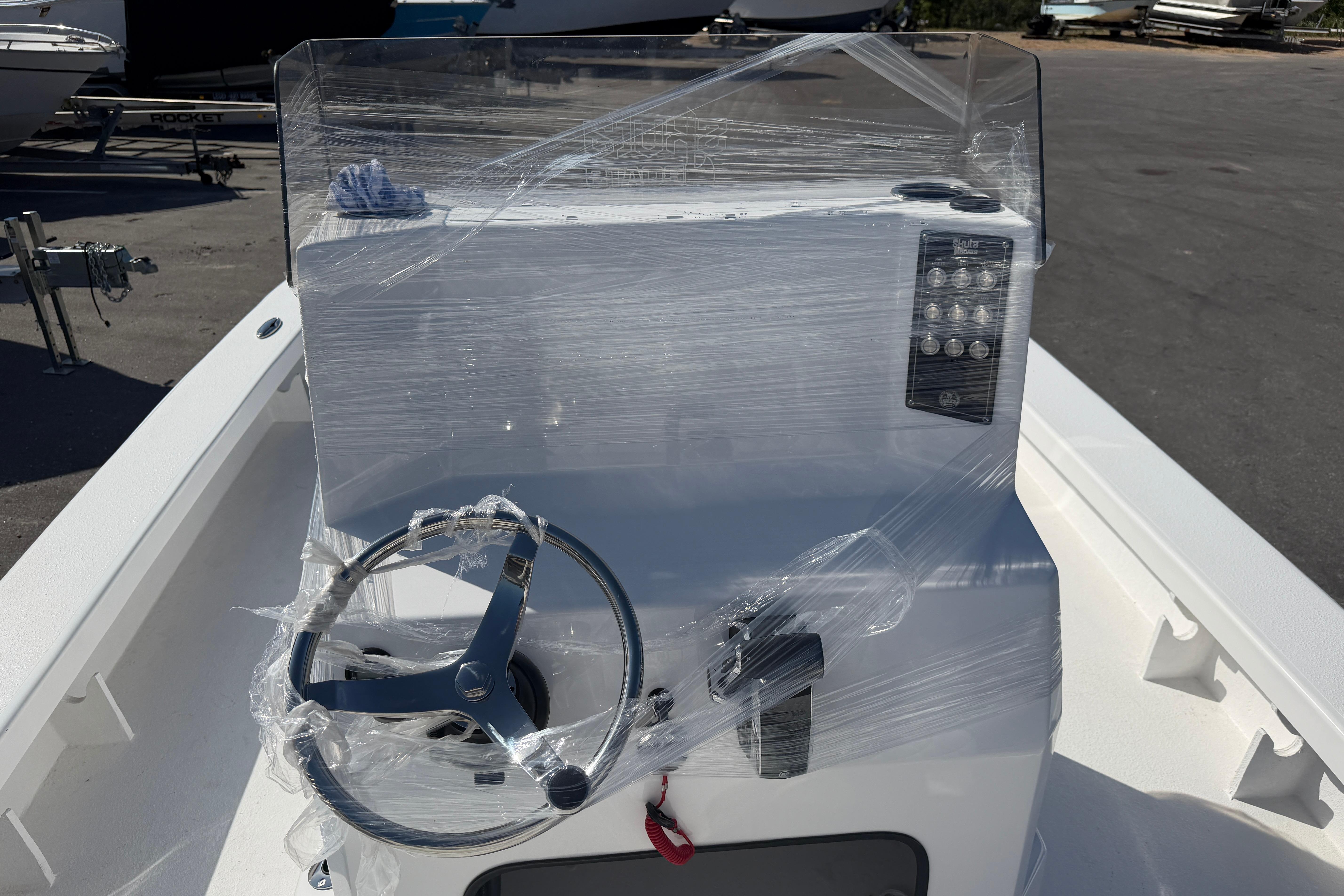 2026 Skuta 24 Cat boat console wrapped in protective plastic, featuring steering wheel and controls.