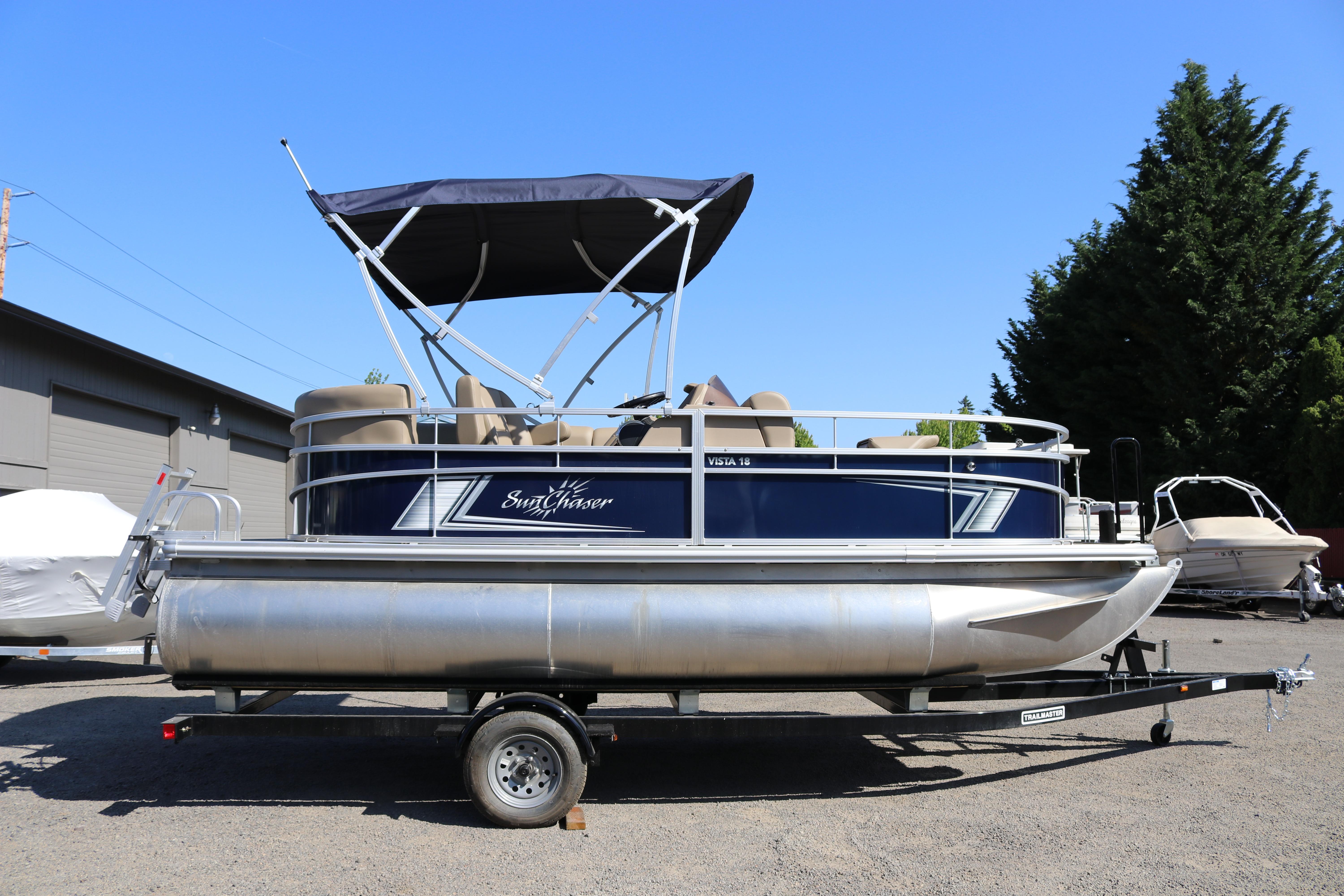 2025 Sun Chaser Vista Fish 18 pontoon boat on trailer, parked outdoors.