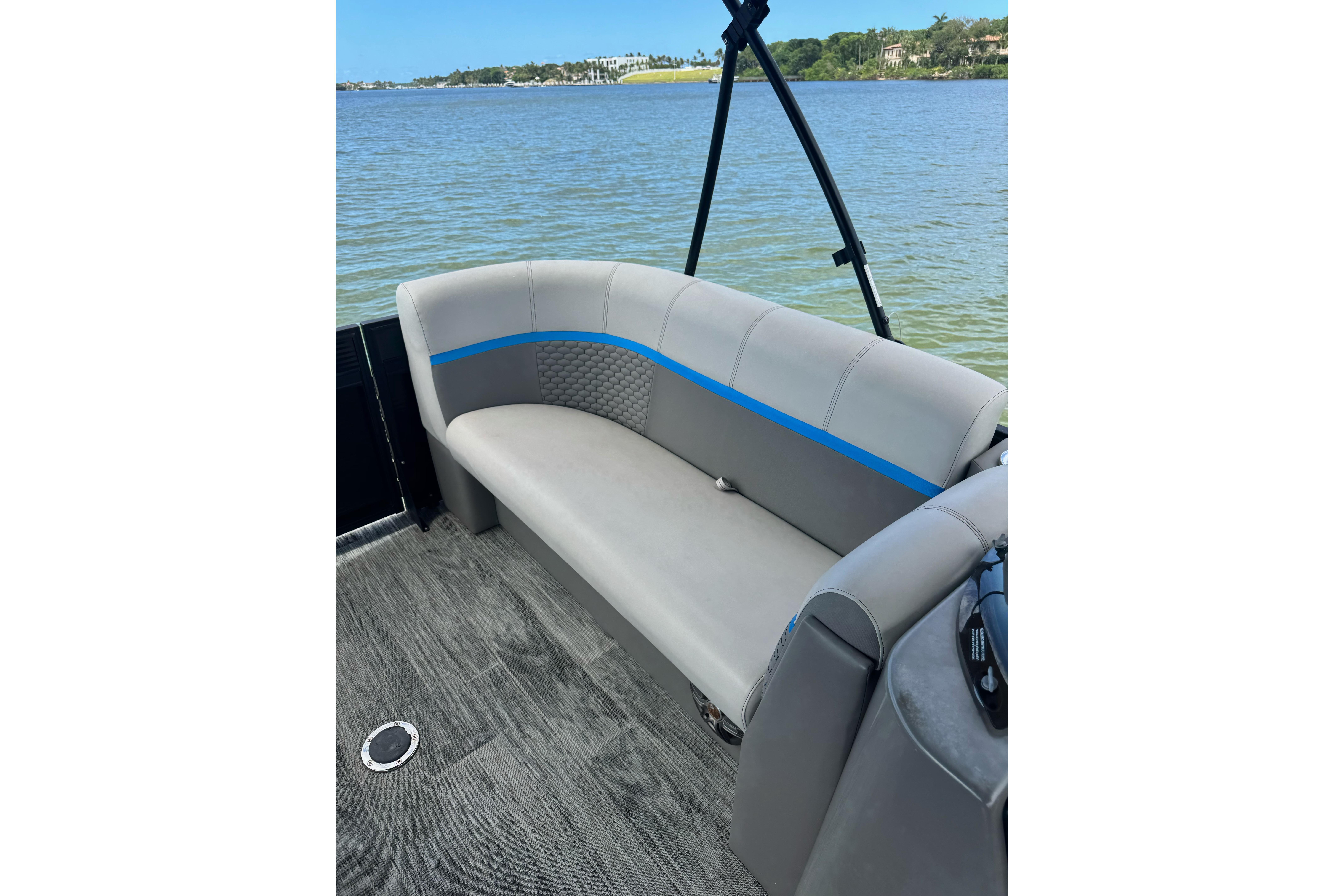 Luxurious seating on 2022 Qwest Edge 820 CTR pontoon boat by the water.