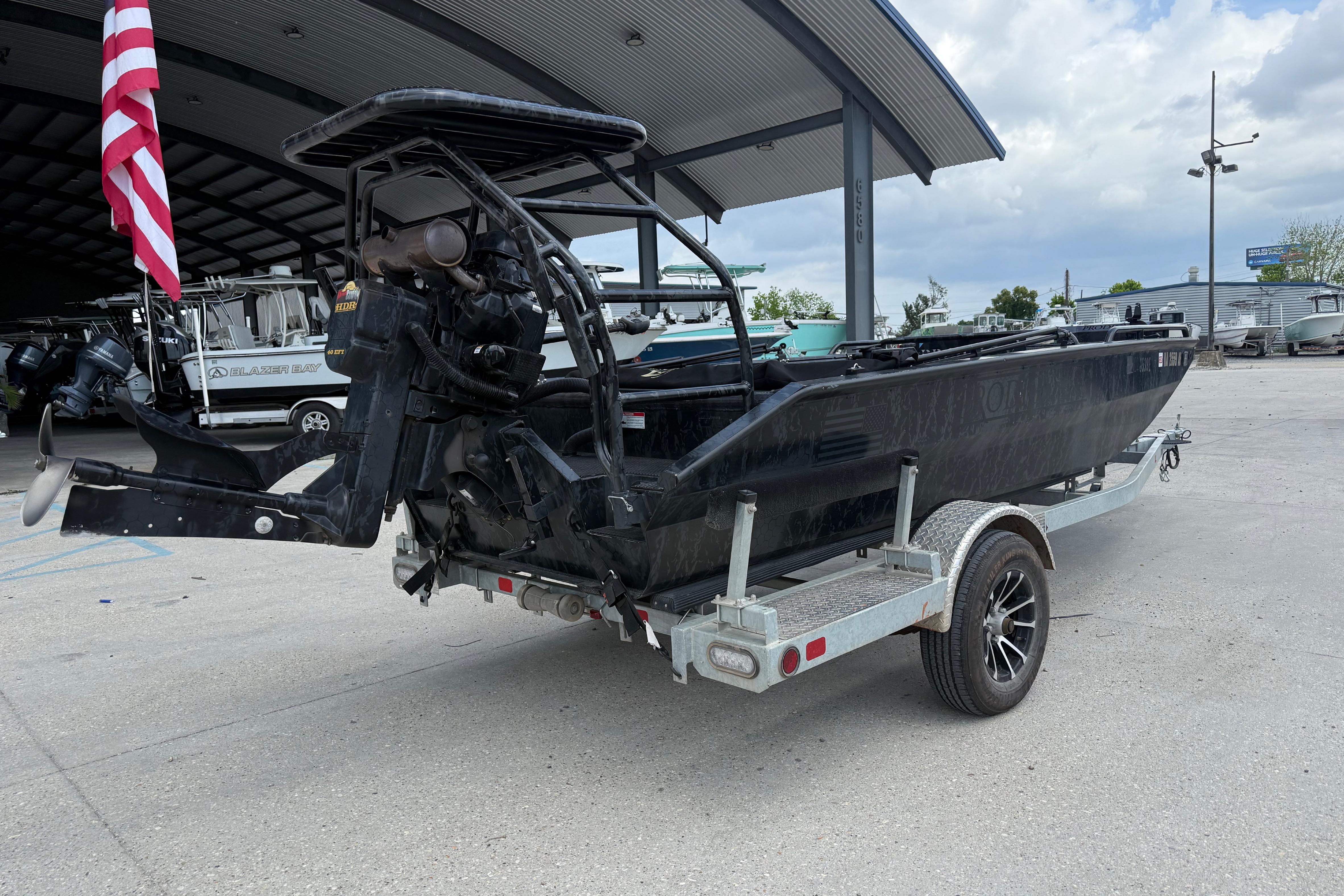2024 Prodigy 17 boat on trailer, parked under a metal canopy with American flag.