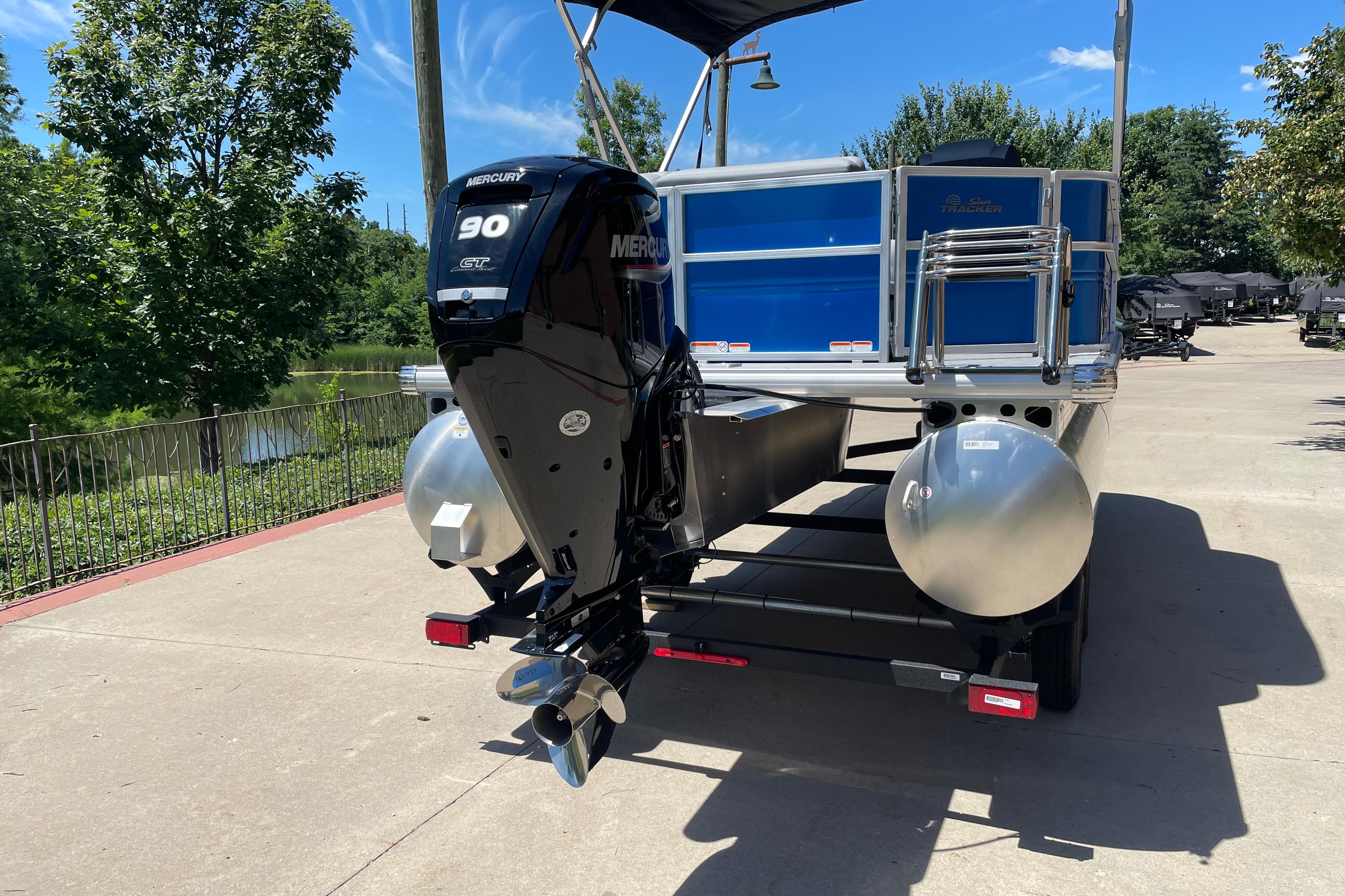 2026 Sun Tracker Party Barge 20 DLX with Mercury 90 HP engine, parked outdoors.