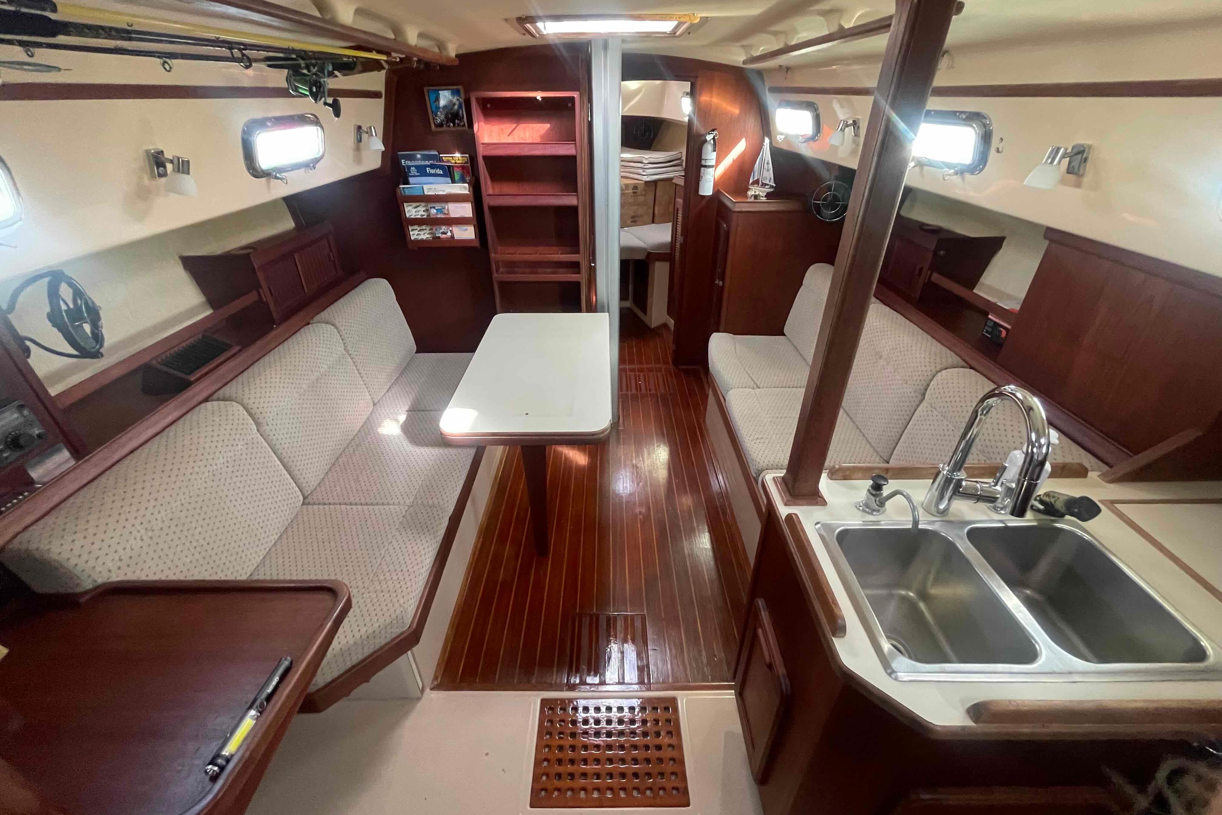 Interior of 1989 Island Packet 35 sailboat with cozy seating and wooden finishes.