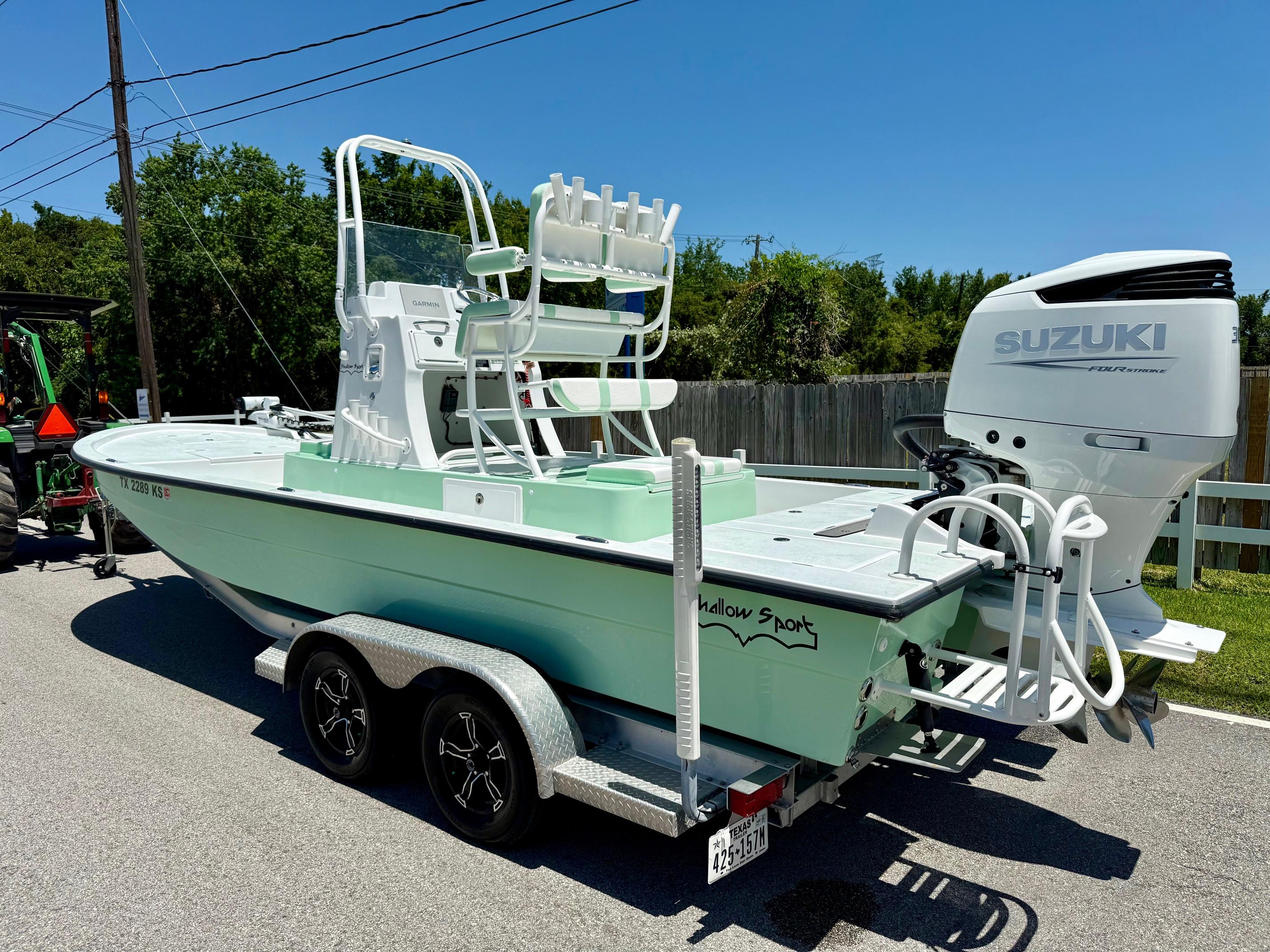 2023 Shallow Sport 24 Sport boat with Suzuki engine on a trailer, parked outdoors.