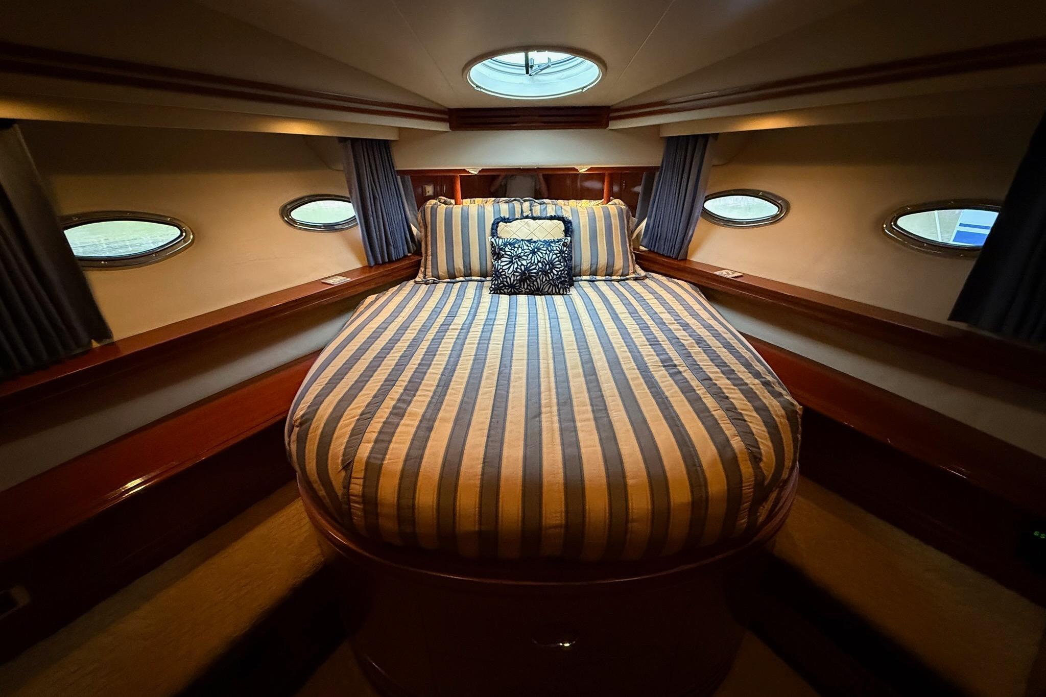 Luxurious bedroom interior of 2006 Carver 56 Voyager yacht with striped bedding.