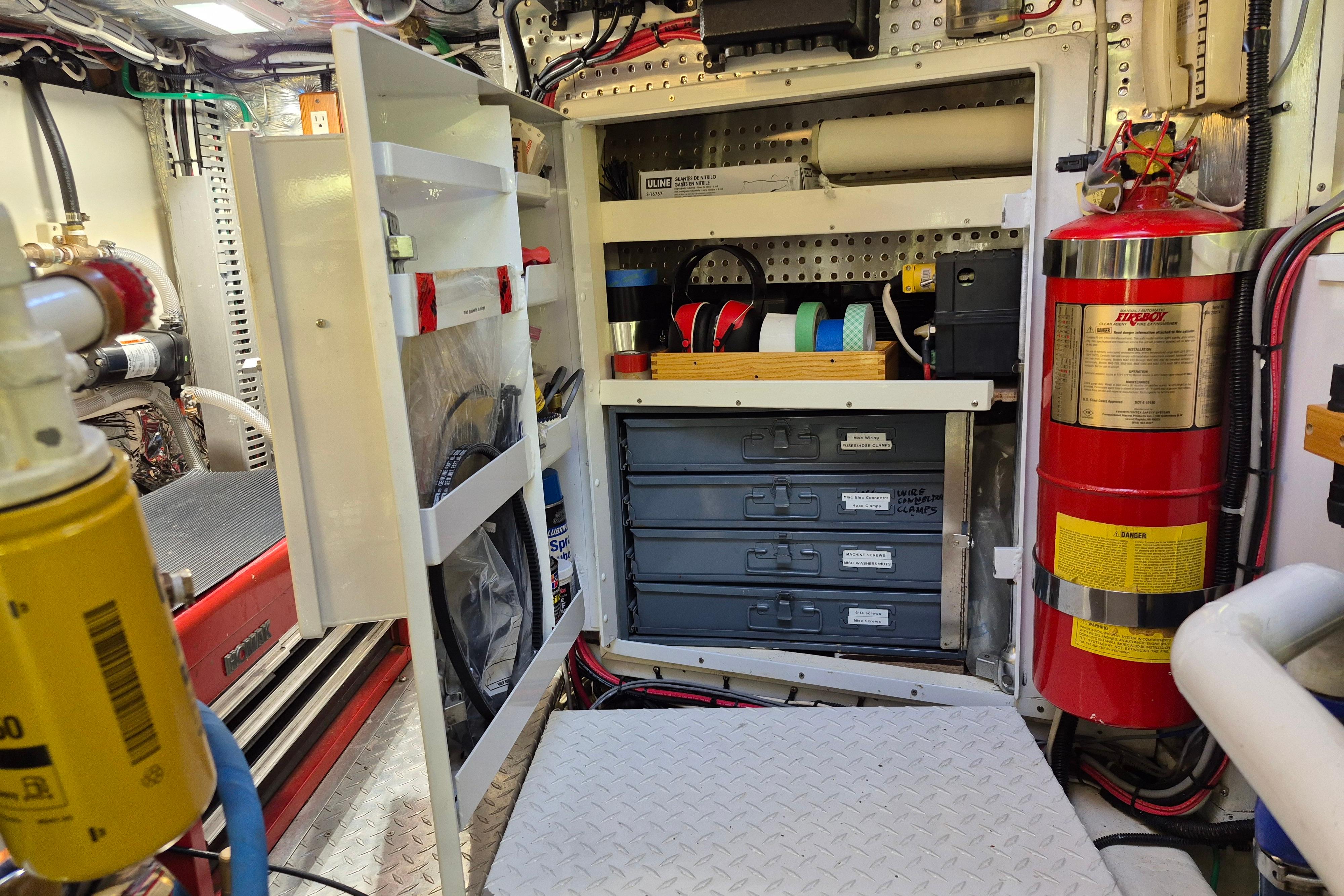 Engine room of a 1990 Camargue 48 yacht with organized tools and fire extinguisher.