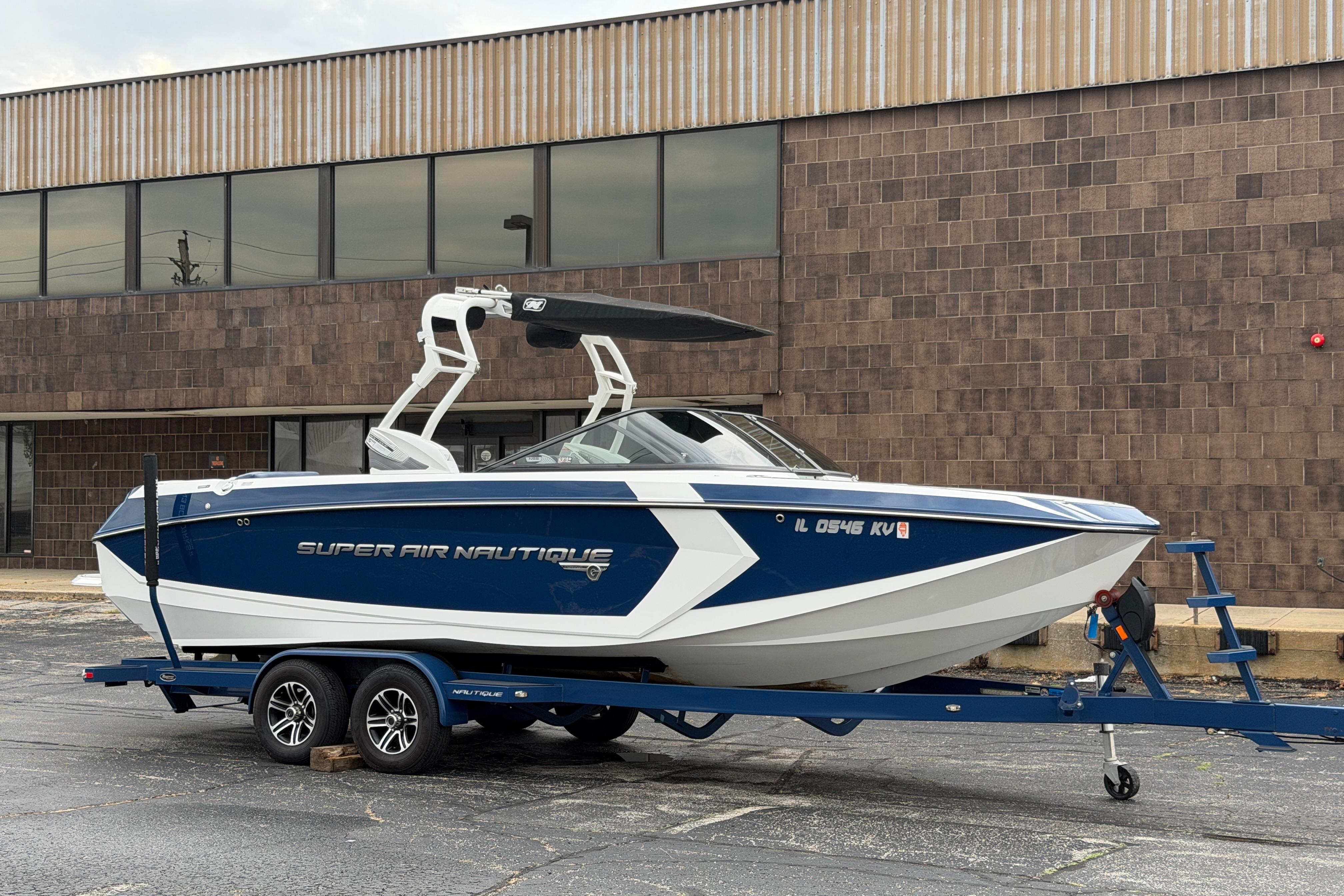 2016 Naitique G25 boat on trailer, parked outside a brick building.