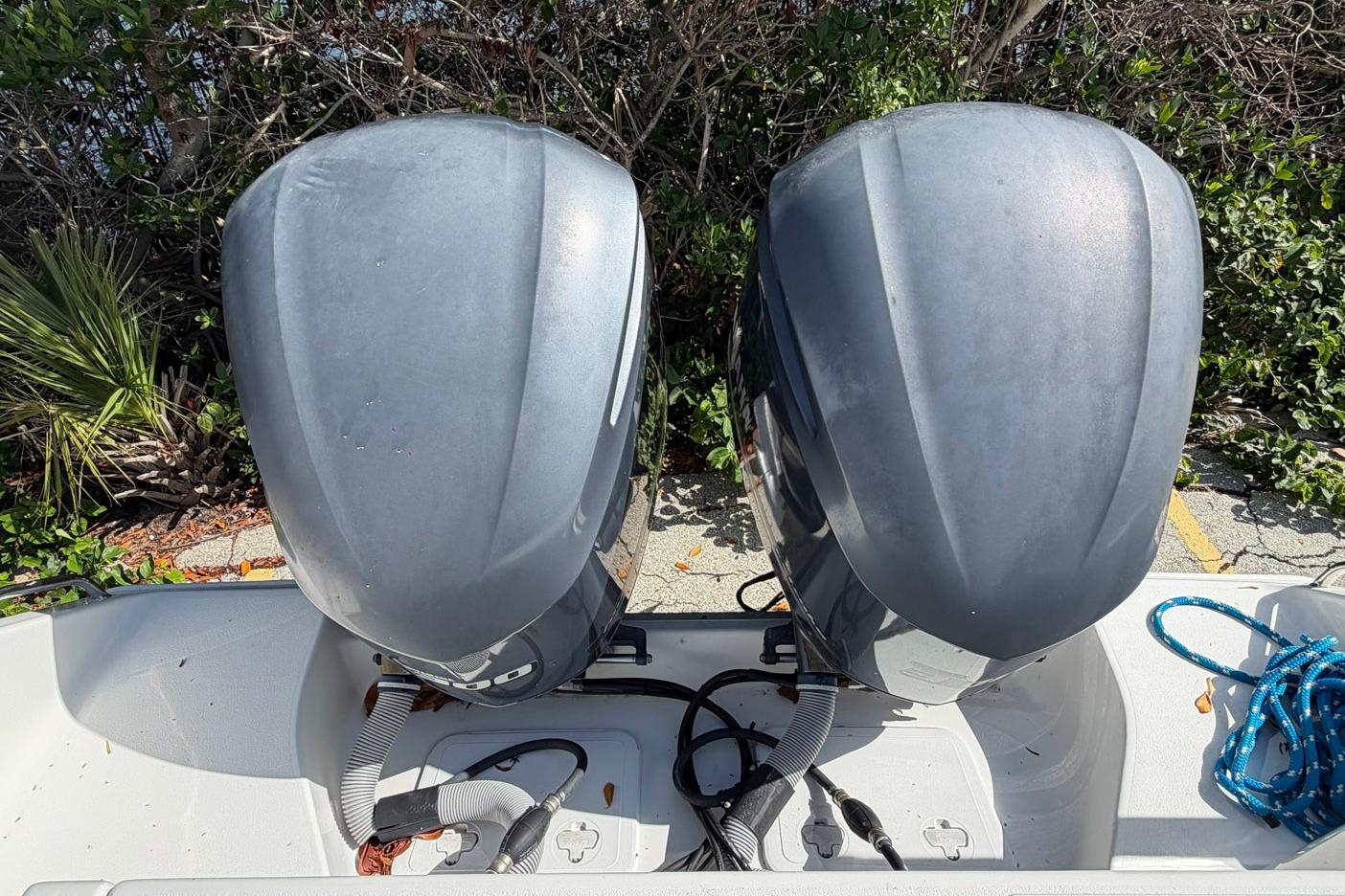 Twin outboard motors on a 2015 Sea Hunt Gamefish 30 boat, surrounded by greenery.