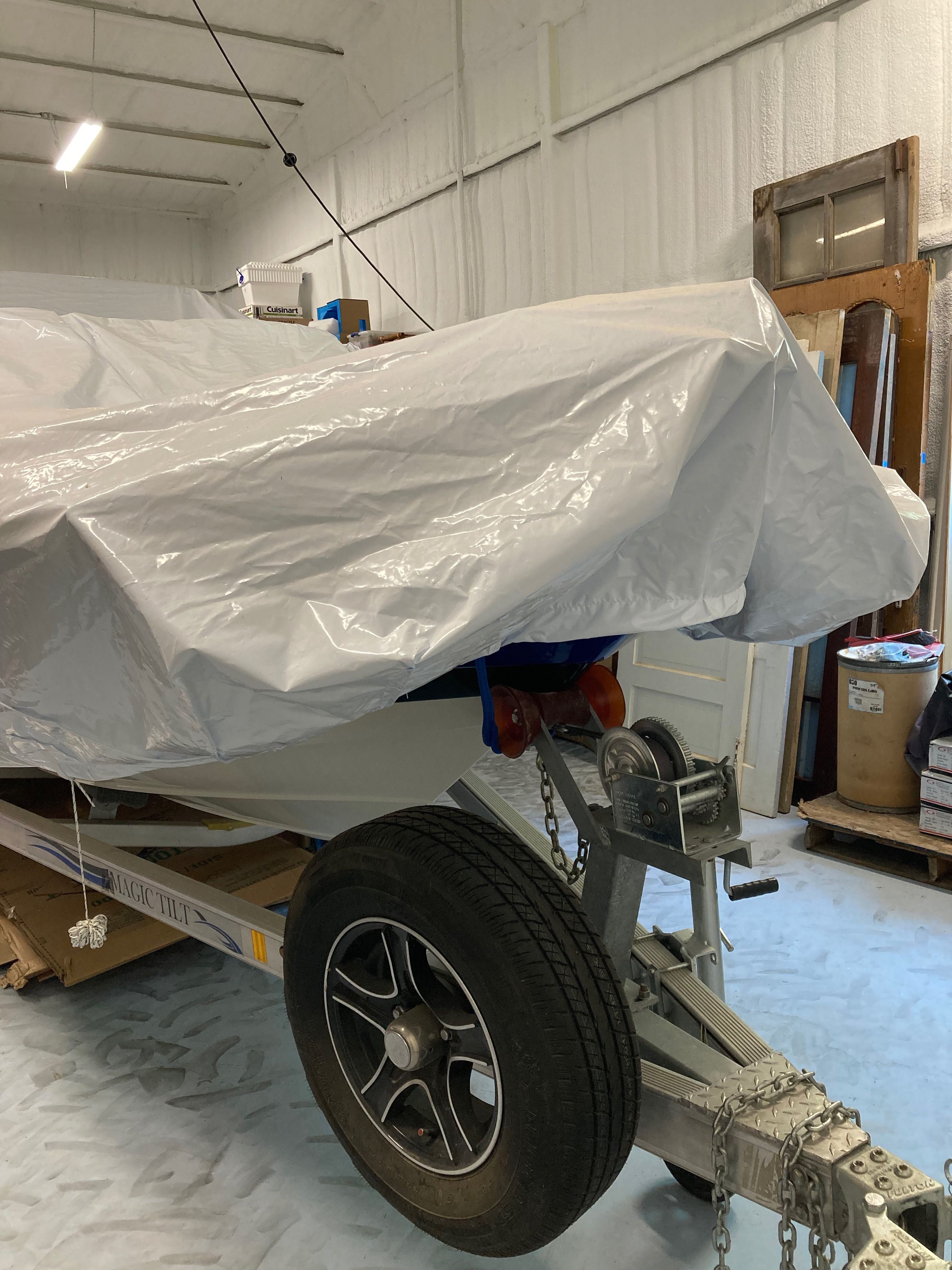 A 2016 Custom 223 DC boat on a trailer, partially covered with a tarp.
