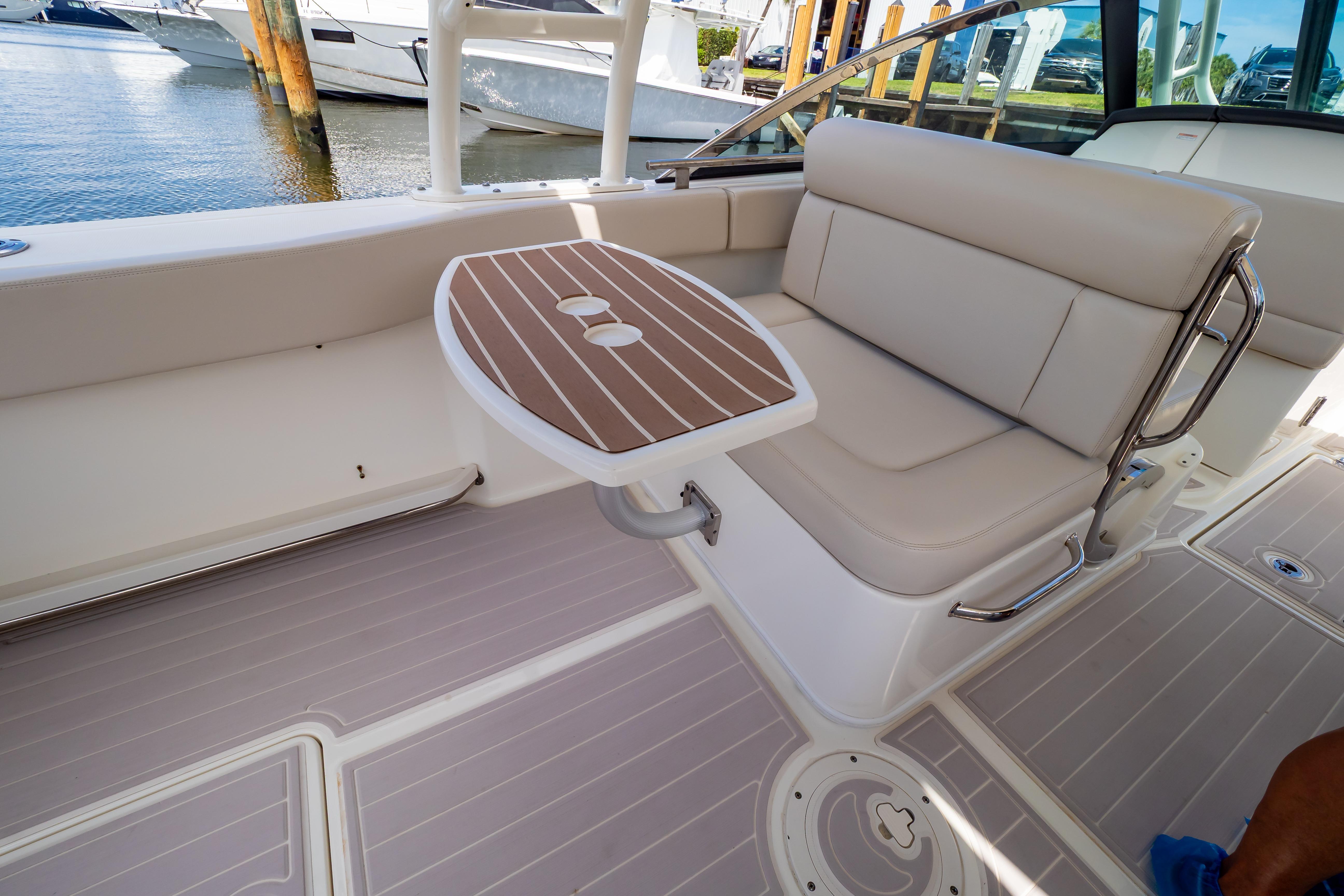 2019 Boston Whaler 270 Vantage interior with seating and table, docked by the water.