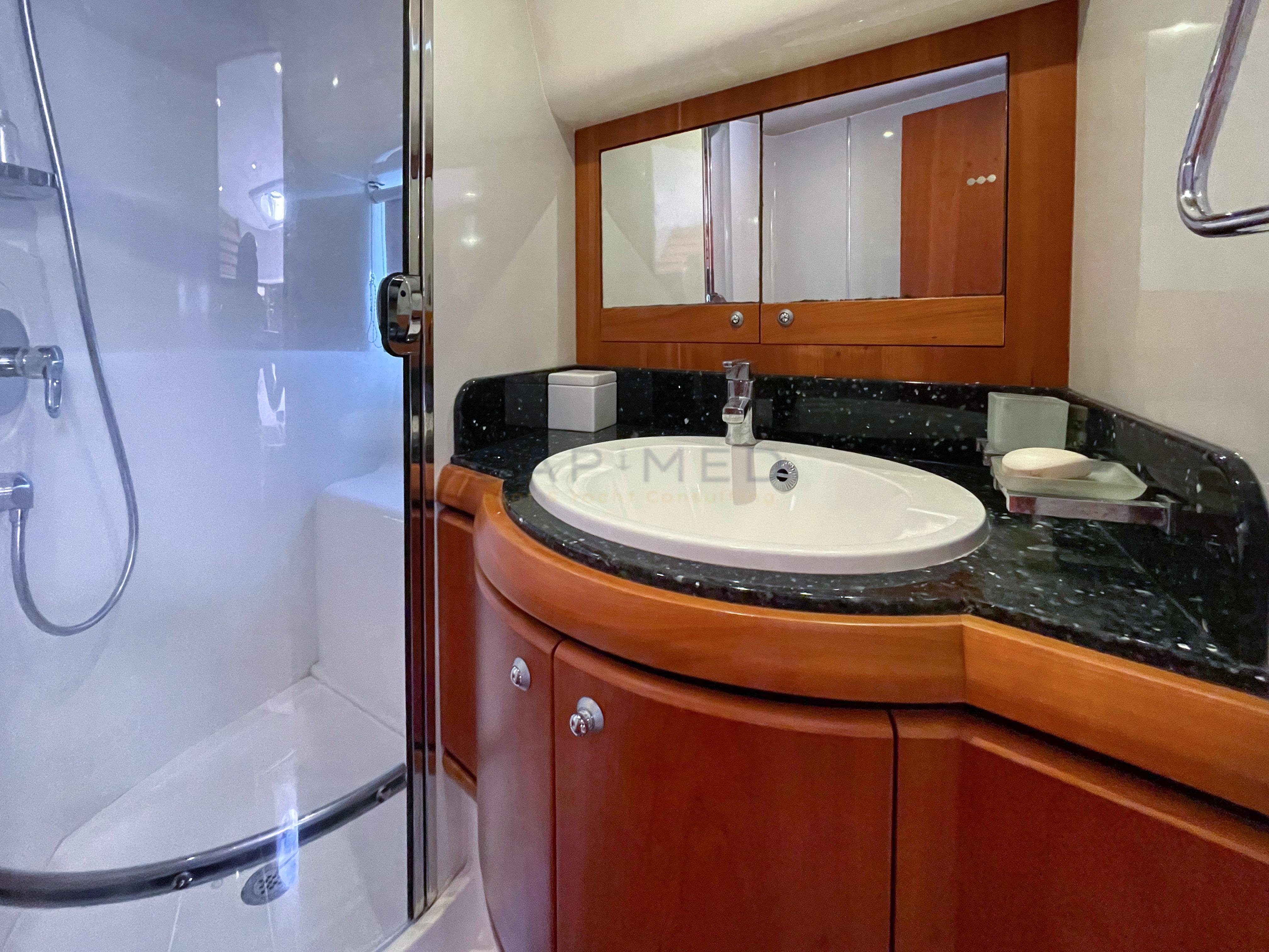 Luxurious yacht bathroom with wood cabinetry, modern sink, and glass-enclosed shower, Pearl 60, 2006 model.