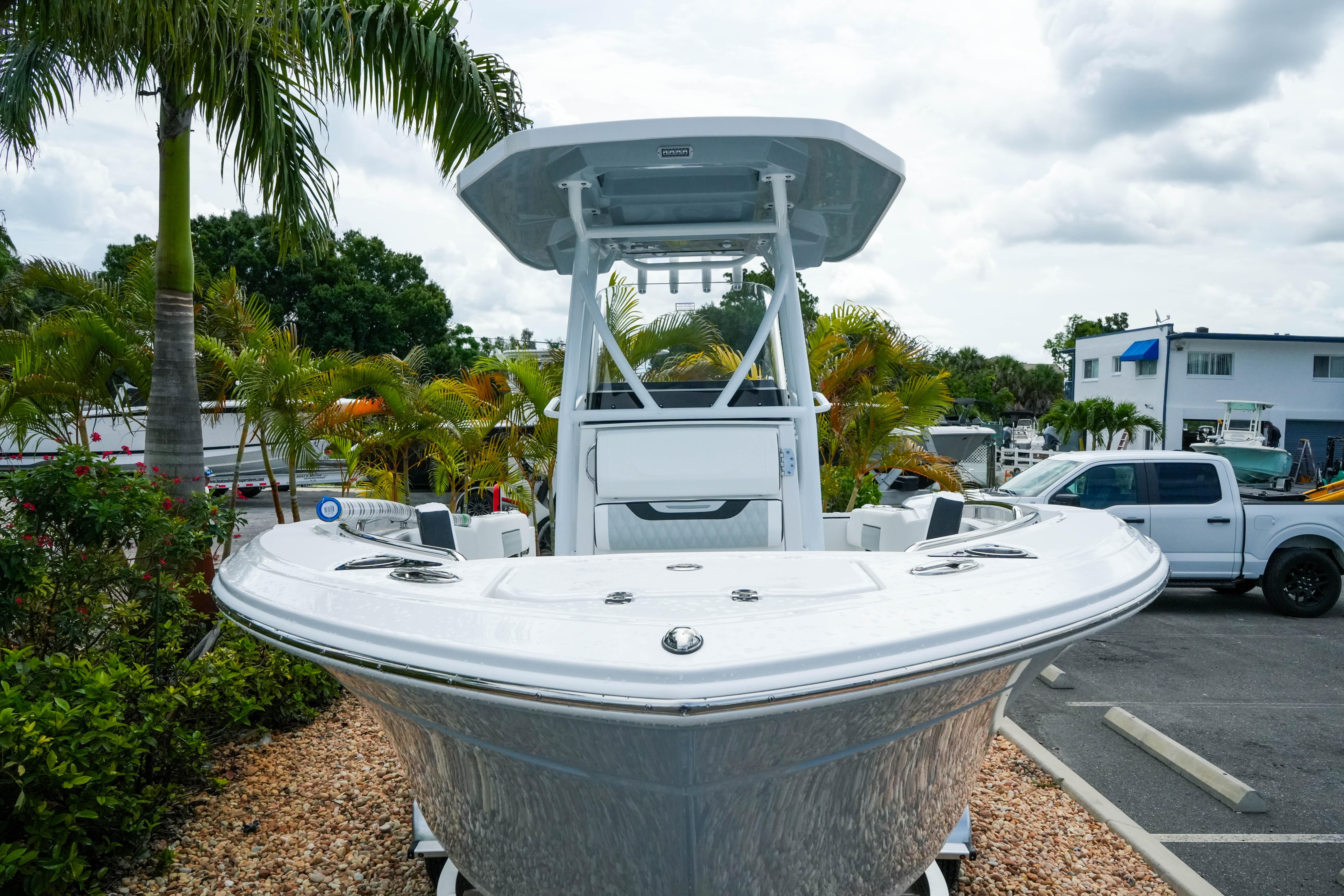 2026 Blackfin 222 CC boat displayed outdoors, surrounded by palm trees and parked vehicles.