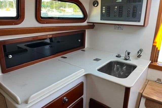 Compact kitchen area in a 2006 Morris 36 boat, featuring a sink and storage cabinets.