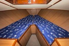 1964 Striker Model 120 boat cabin with blue patterned bedding and wooden interior.