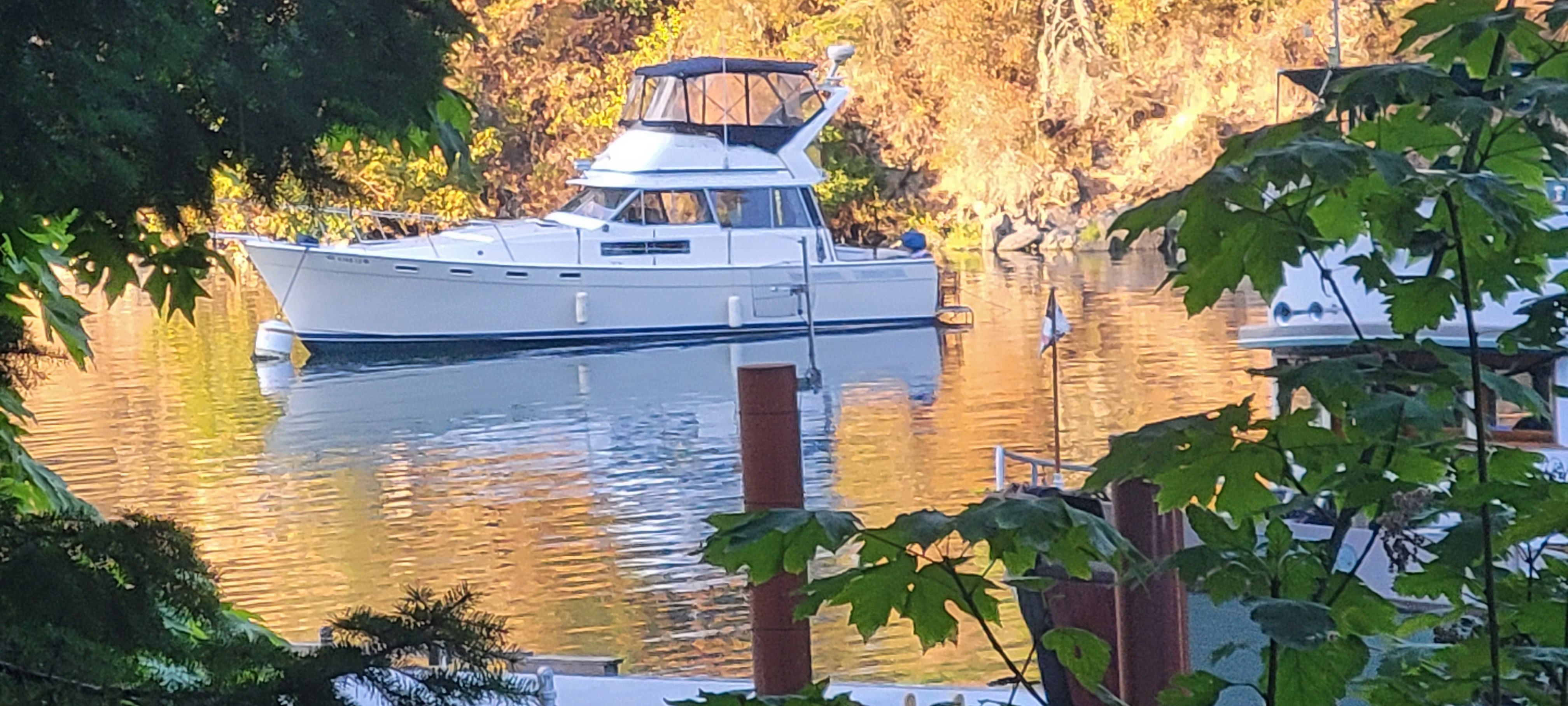 1984 Bayliner 3870 Motoryacht on calm water surrounded by autumn foliage.