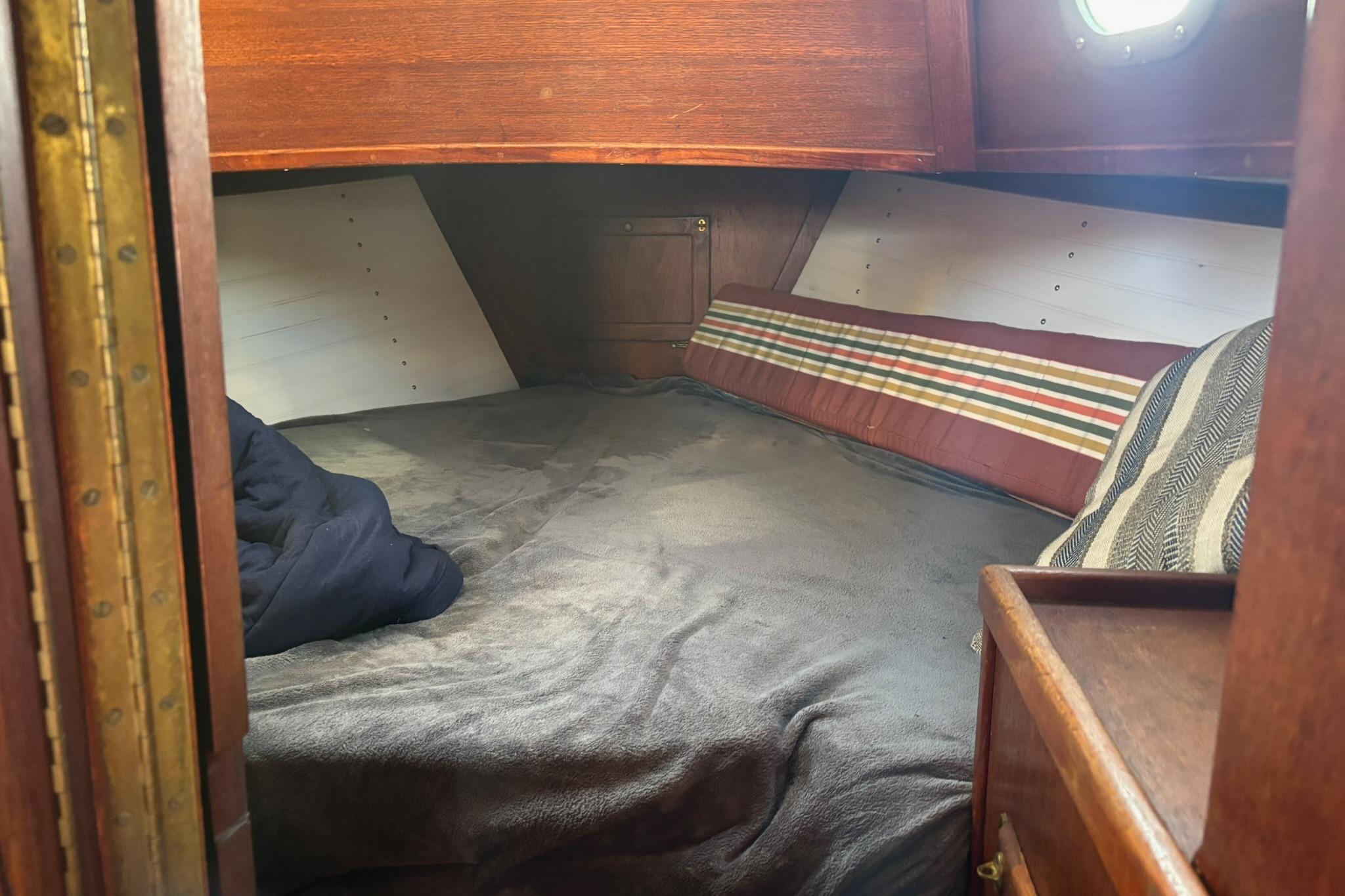 Cozy cabin interior of a 1977 Pacific Seacraft 31 sailboat with striped cushions.