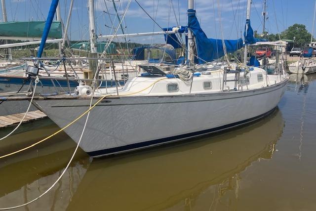 1979 Pearson 365 Ketch sailboat docked in a marina, featuring blue sails.