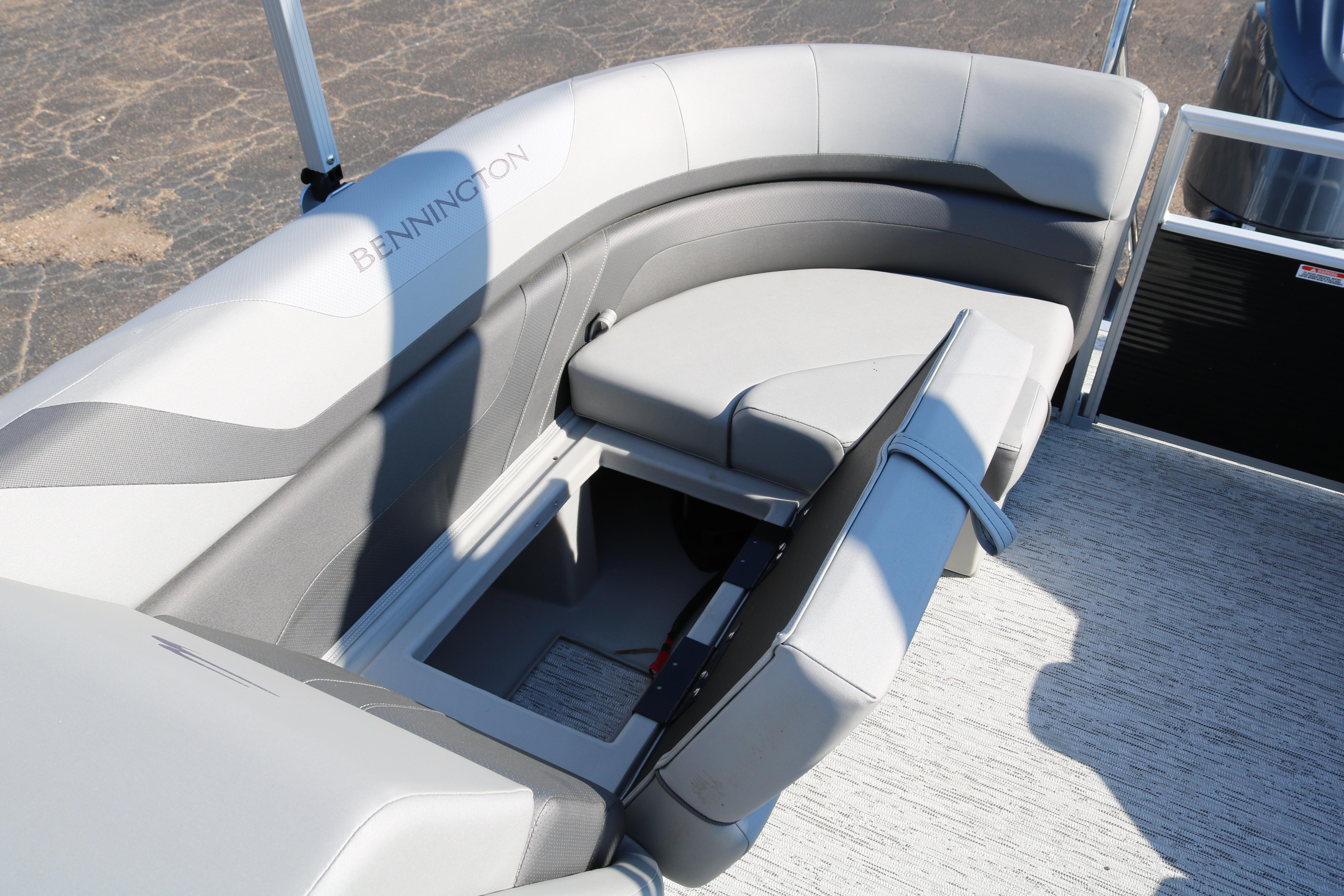 2026 Bennington 22SX Stern Radius boat with open storage compartment and cushioned seating.