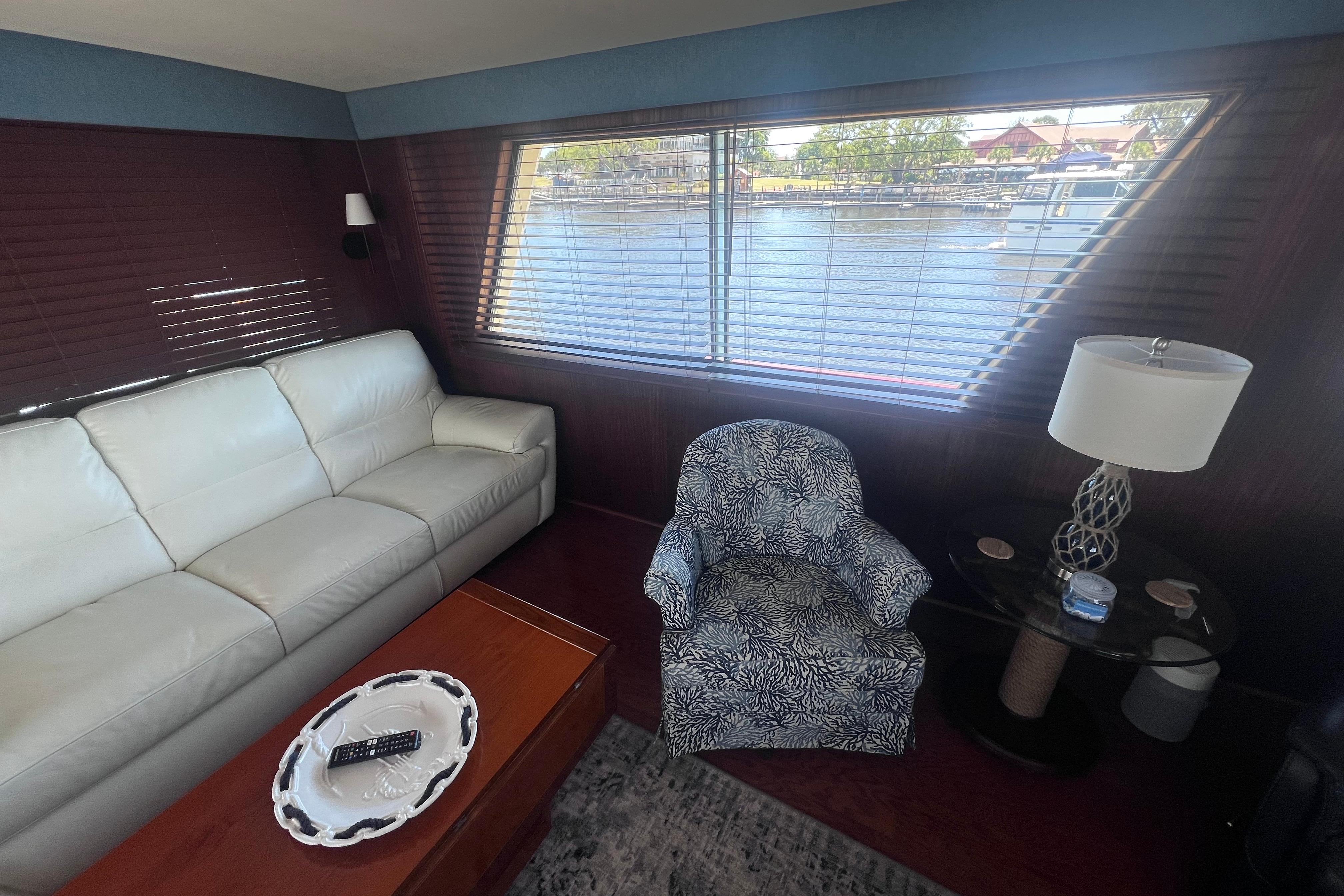 Interior of 1987 Hatteras 70 Cockpit Motor Yacht with sofa, armchair, and window view.