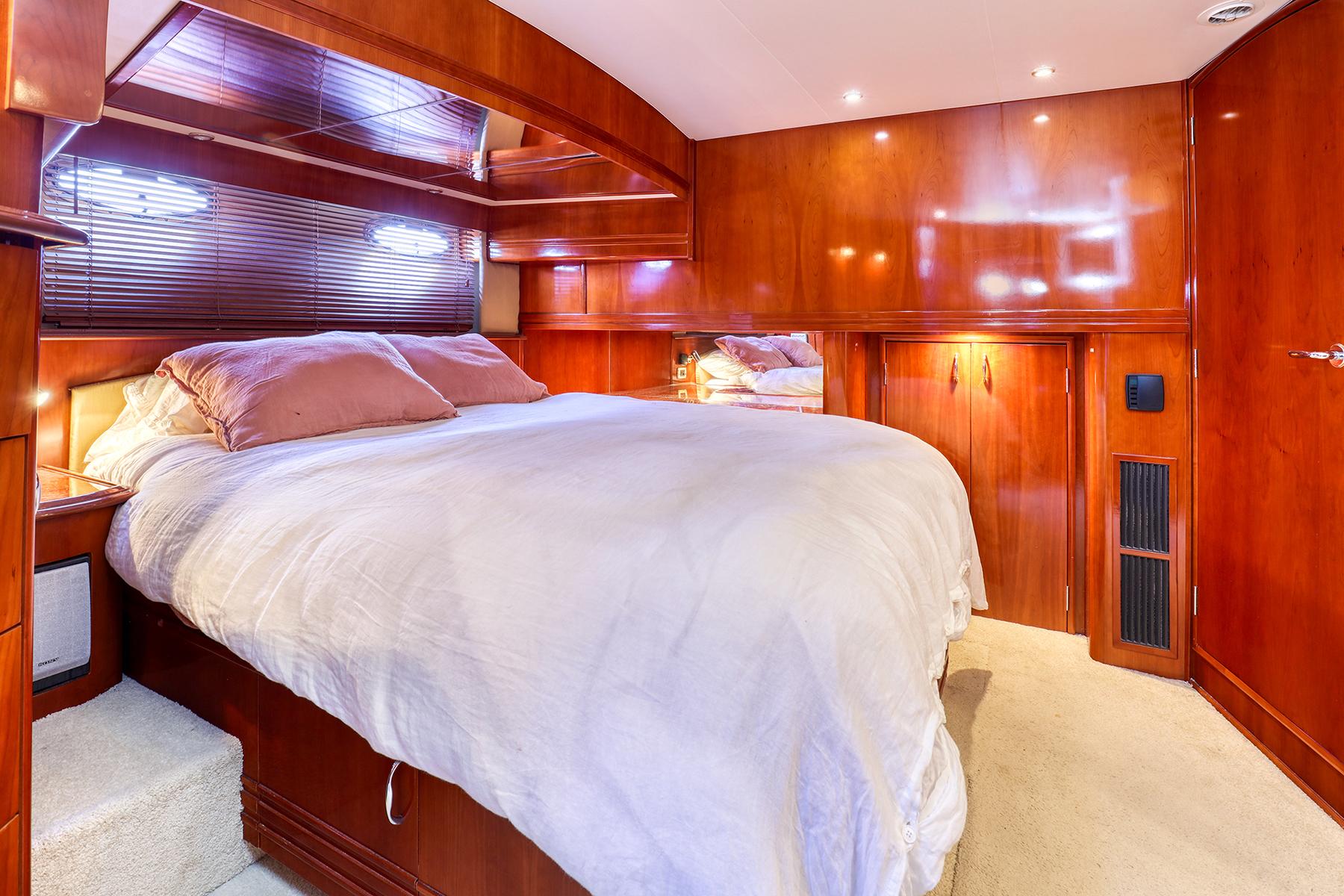 Luxurious bedroom interior of 2005 Carver 560 Voyager yacht with wooden finishes.
