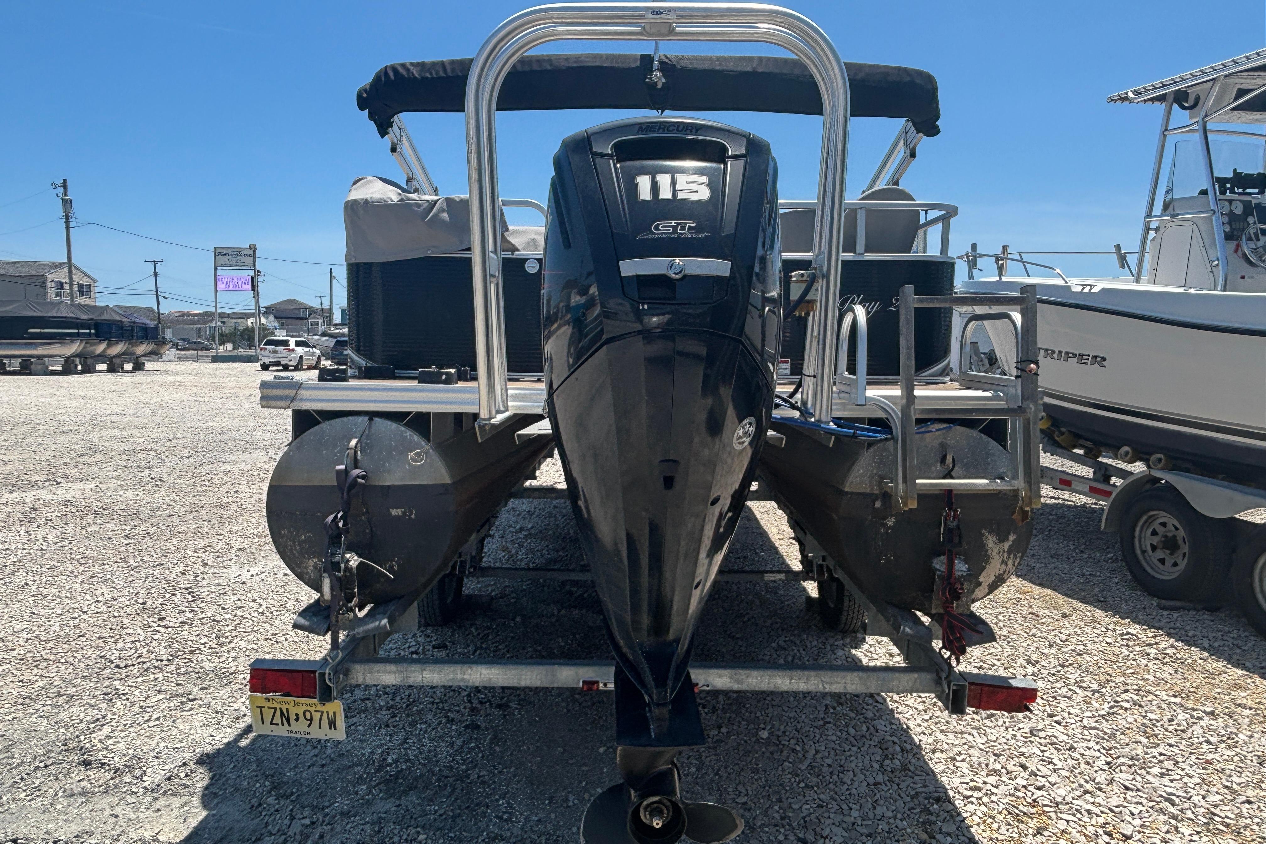 2017 Qwest LS 822 Bar pontoon boat with Mercury 115 GT engine, parked on gravel.