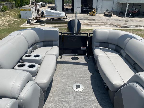 2023 Regency 250 LE3 pontoon boat with spacious seating and cup holders, docked near a storage facility.
